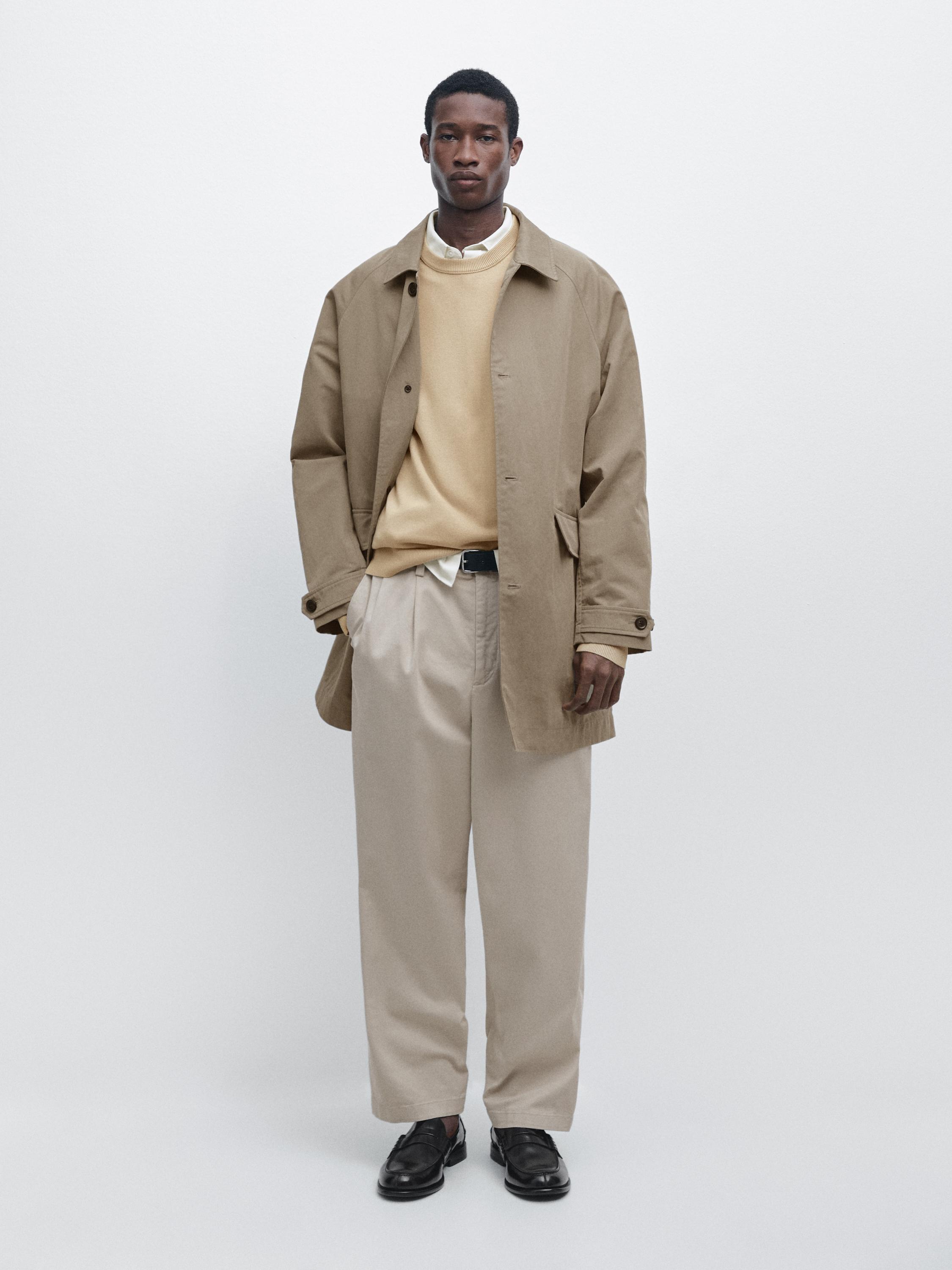 Ensemble composé d'un trench beige à col revers, d'un pull crème, d'une chemise blanche, d'un pantalon beige et de mocassins noirs.