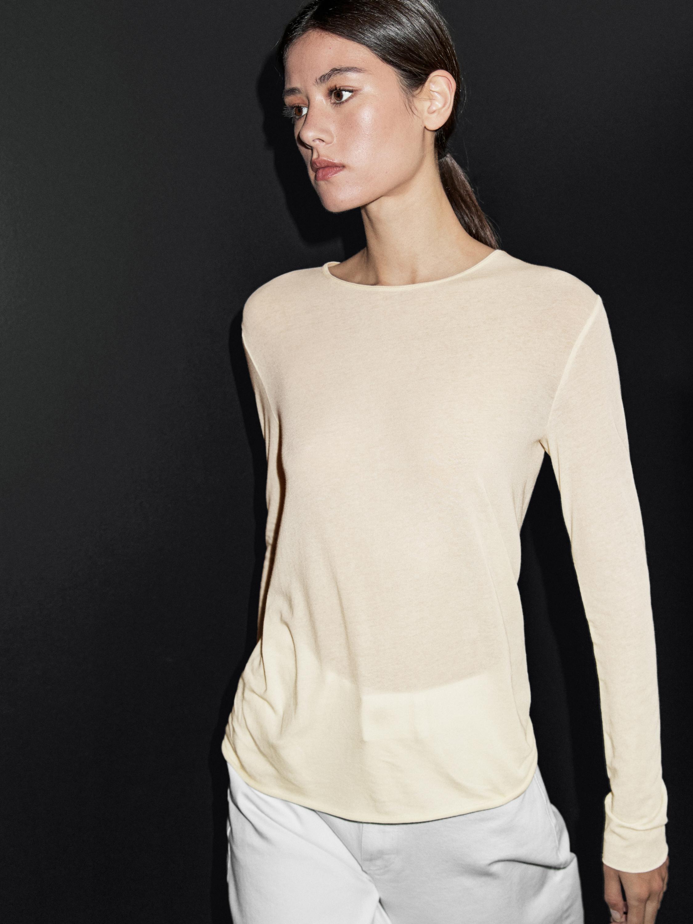 Среден кадар на маица со долги ракави, пастелно розова, со округло деколте, без видливи принтови.