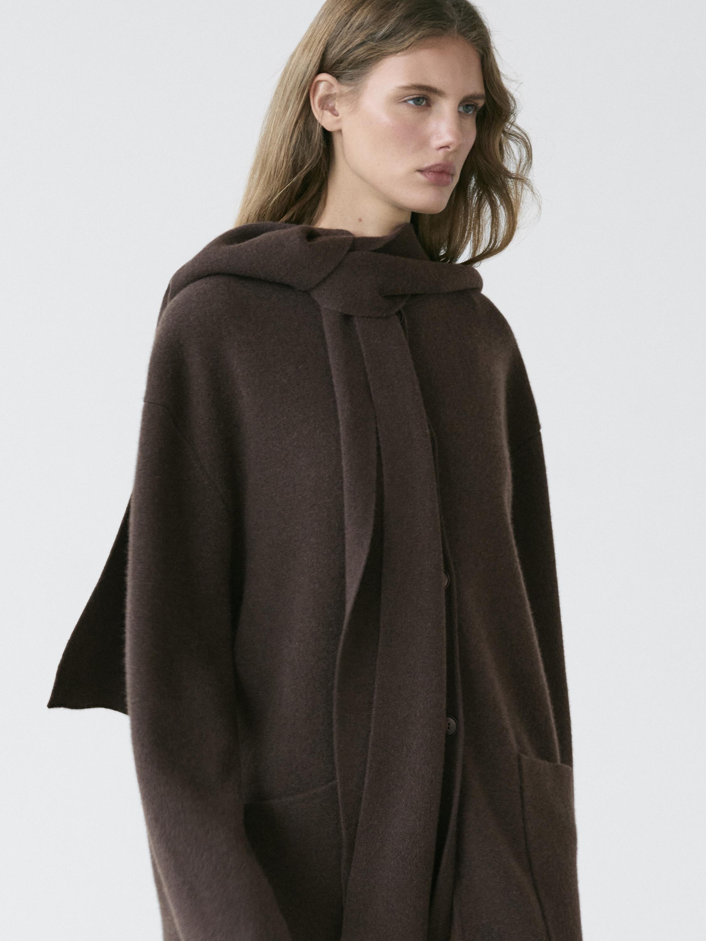 Medium shot of a long brown jacket with a hood and scarf, visible side pockets.