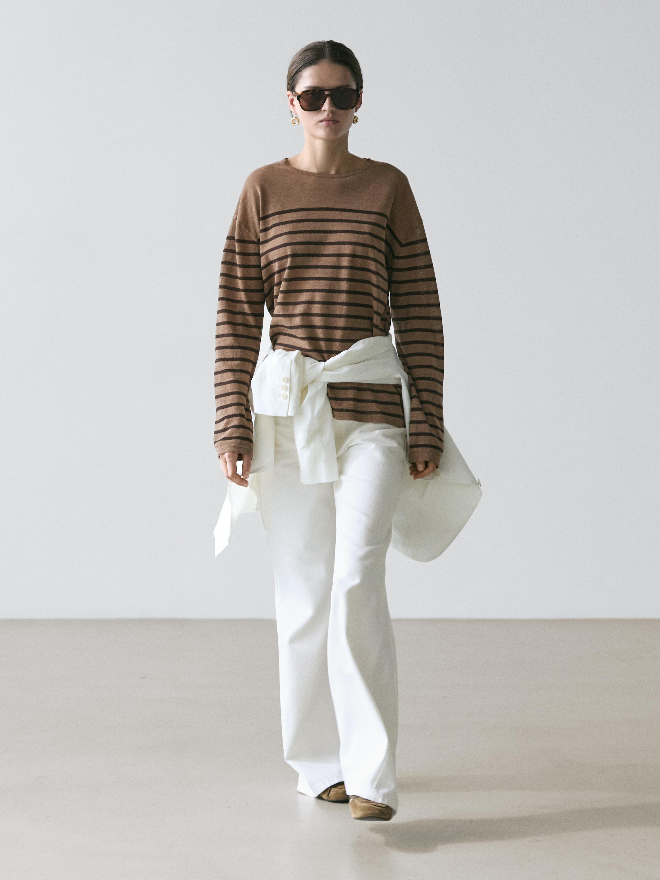 Zestaw składający się z brązowej koszulki w paski z długim rękawem i białych dzwonów.