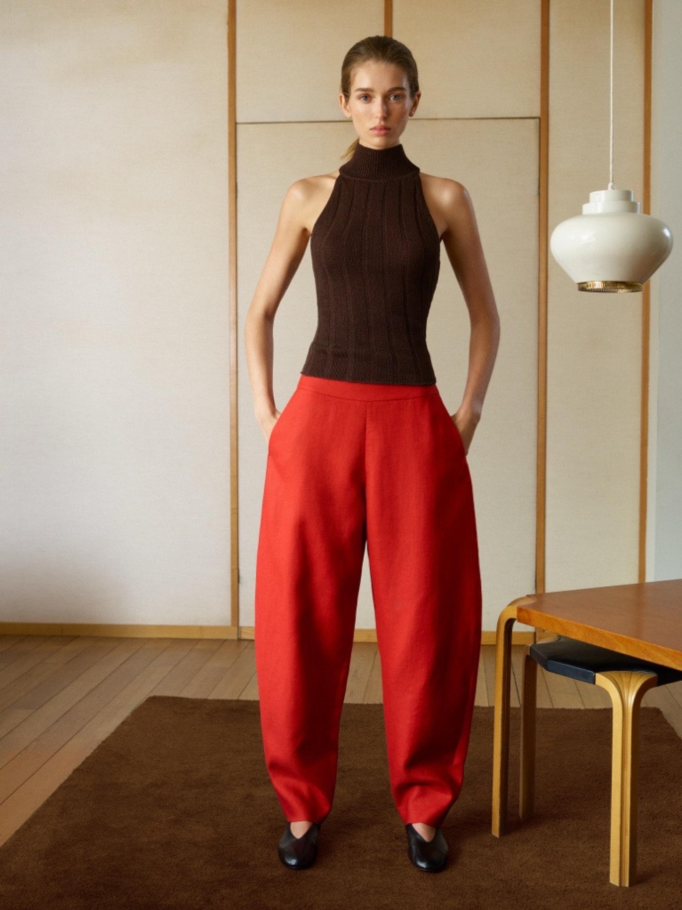 Set atasan tanpa lengan kerah tinggi warna cokelat dan celana panjang lebar merah dengan saku samping.