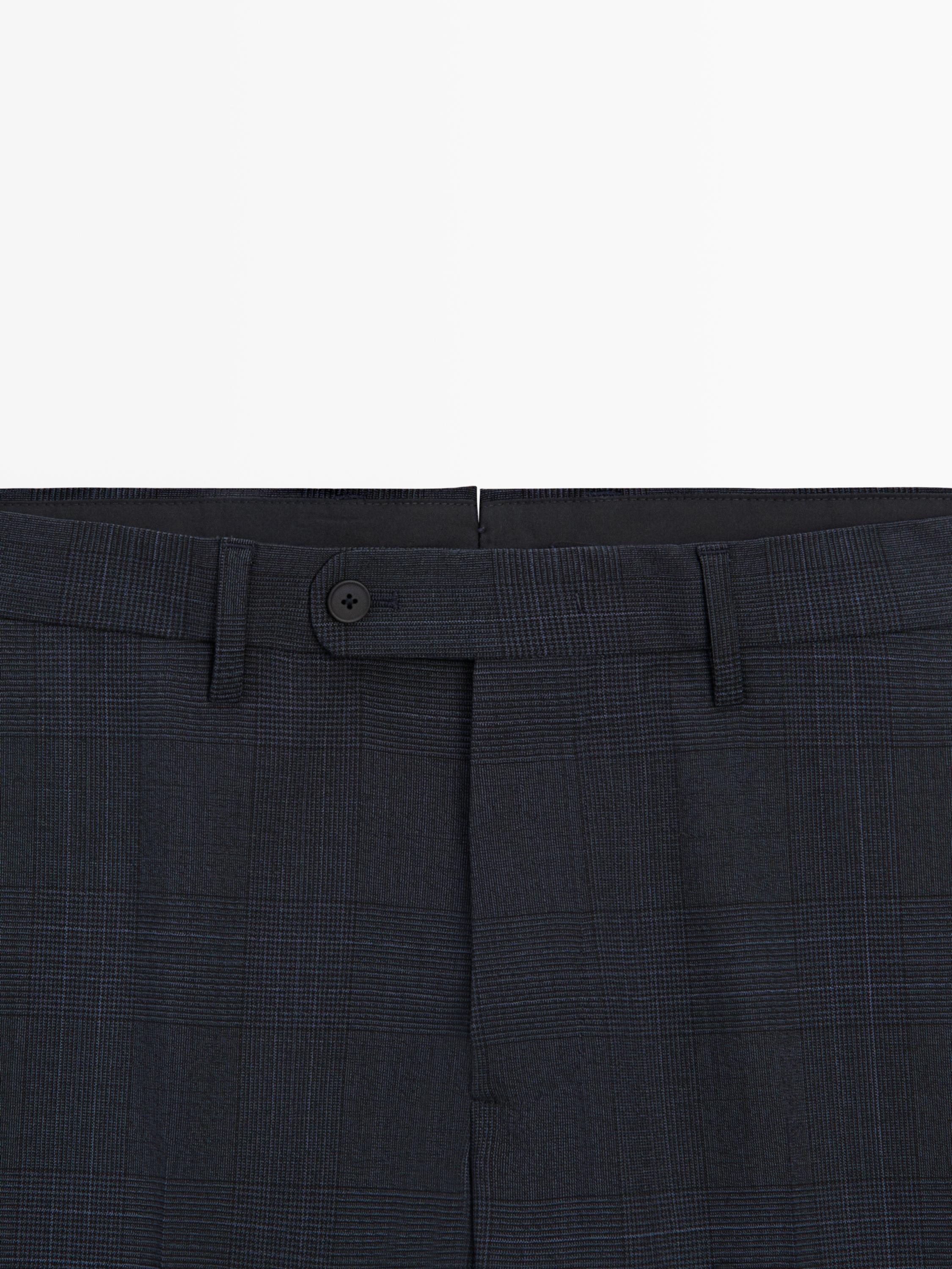 Plan moyen de la taille d'un pantalon bleu marine avec bouton sur le devant et imprimé à carreaux.