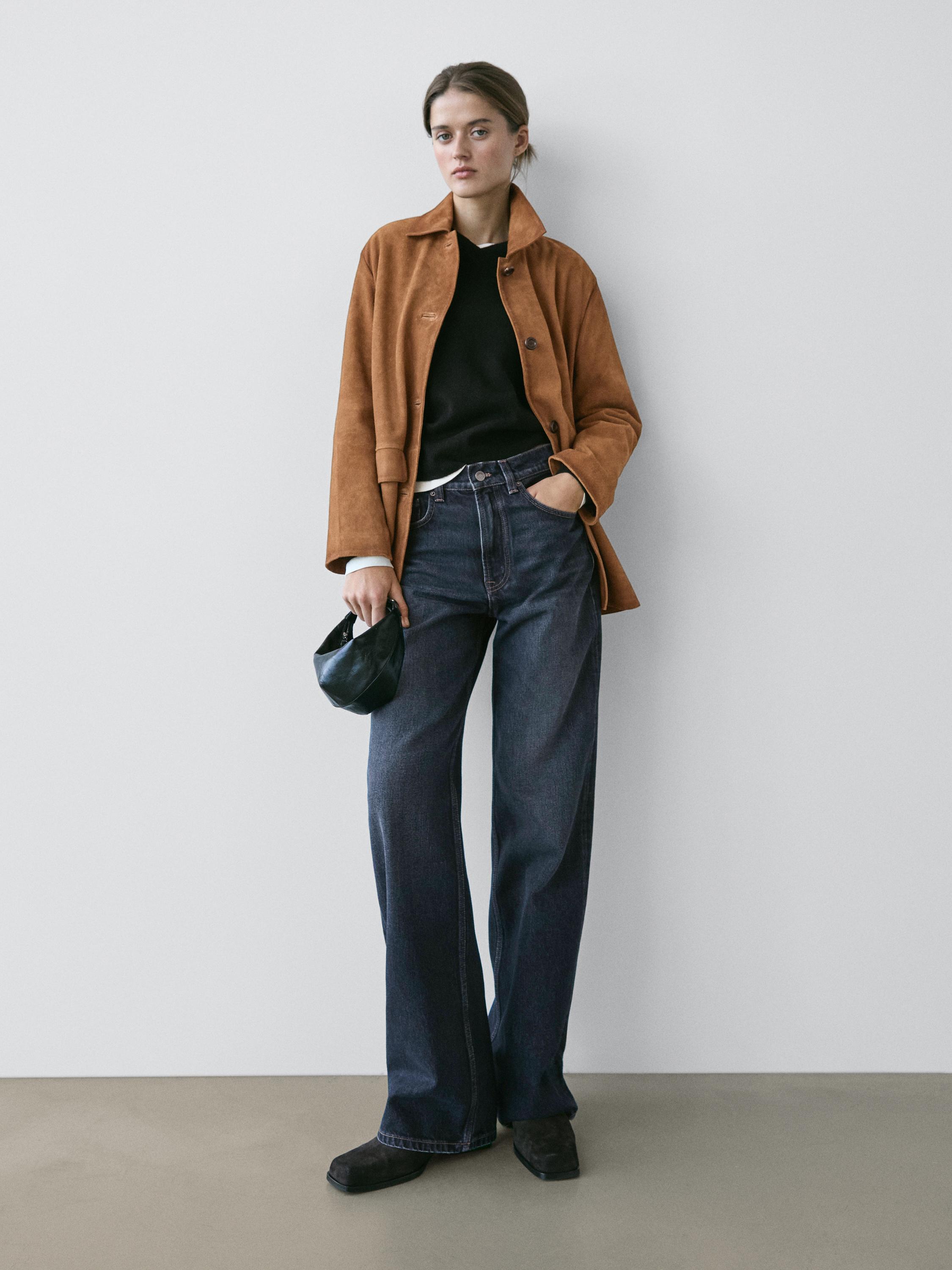 Ensemble composé d'une veste marron, d'un t-shirt noir et d'un jean bleu foncé à jambes larges avec une taille haute et des poches latérales.