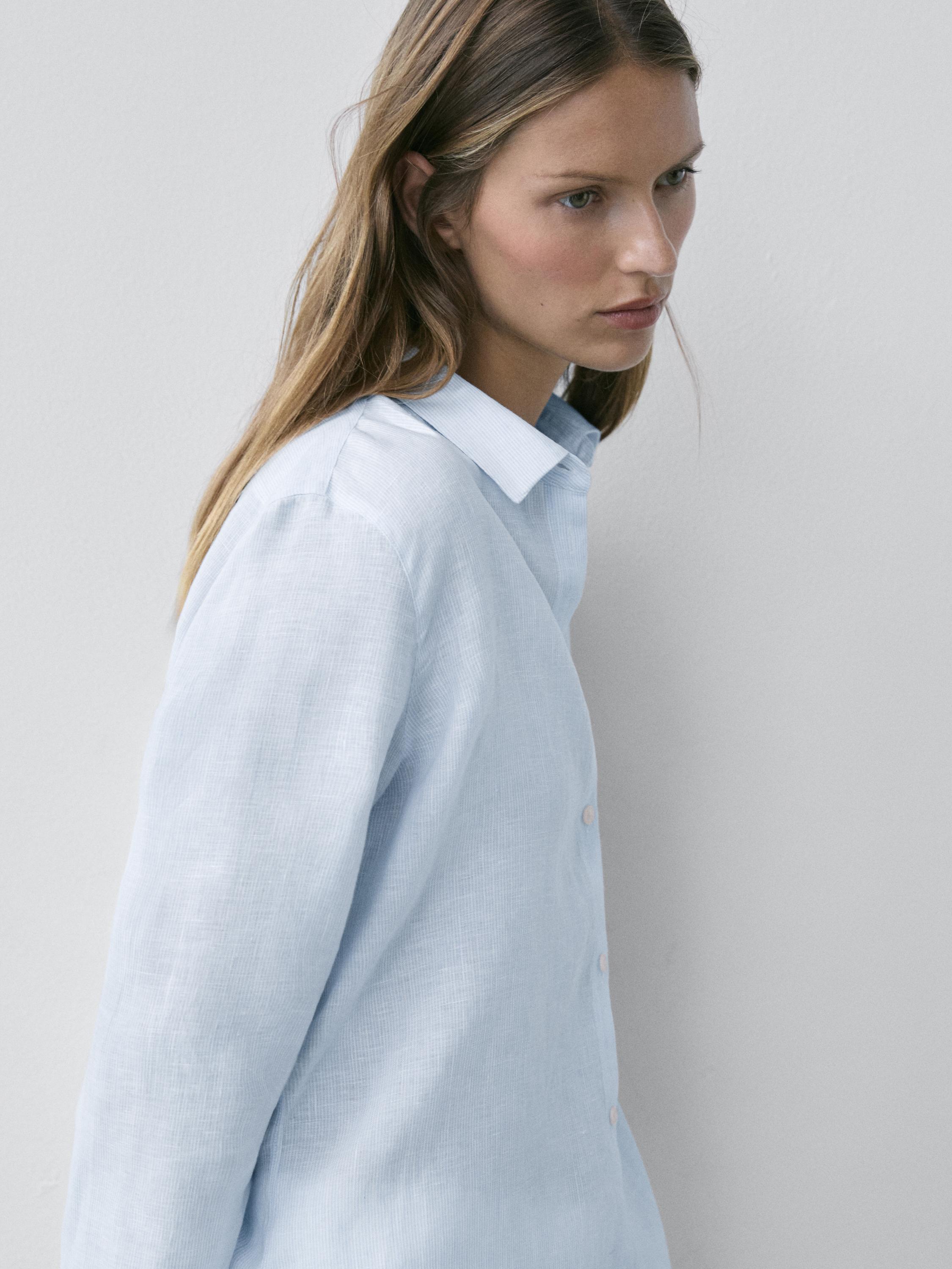 Plano médio de camisa azul-celeste com gola clássica e abotoadura frontal.