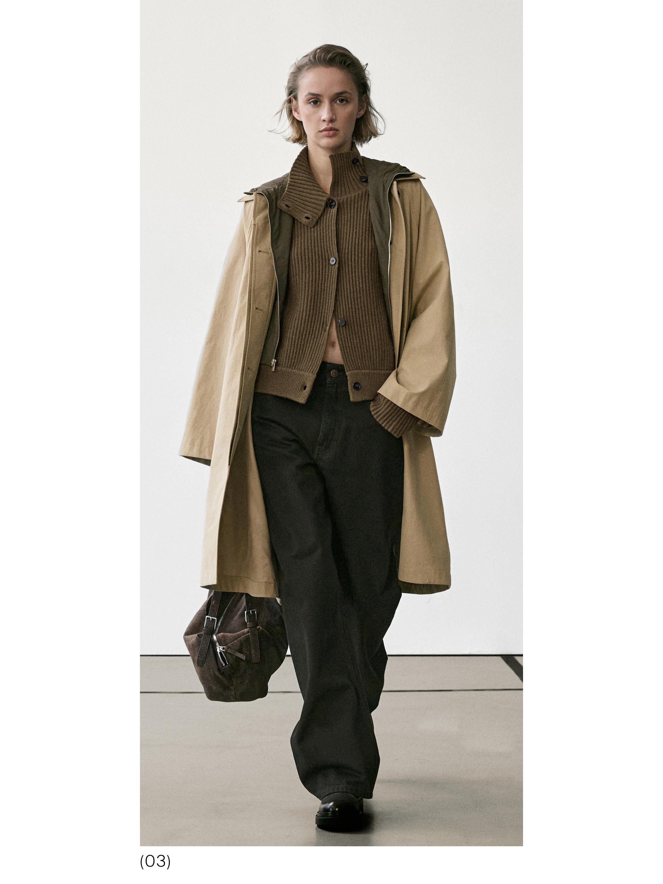 Conjunto de abrigo beige largo, cárdigan marrón con botones, pantalones negros anchos y bolsa marrón.