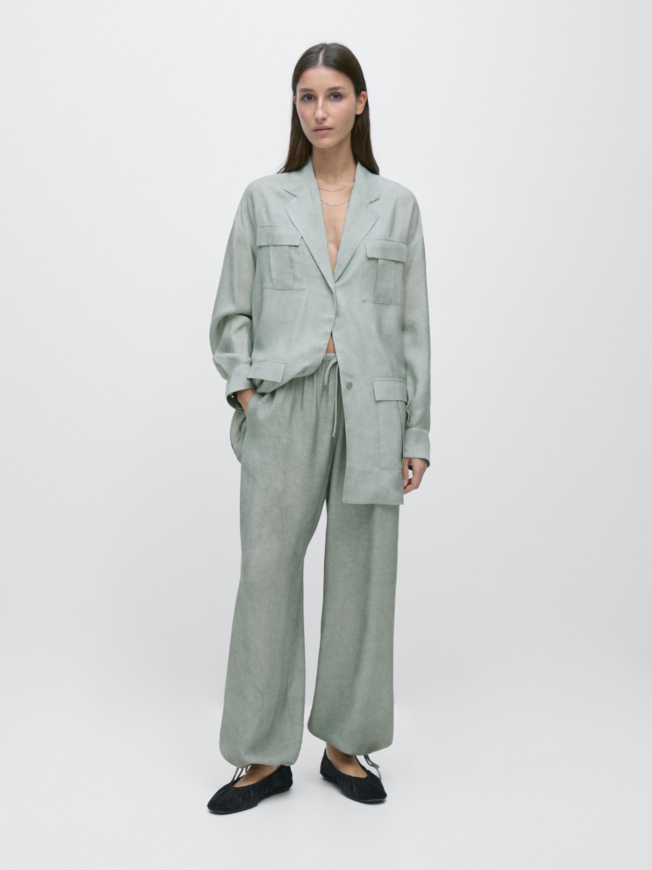 ชุดเสื้อเชิ้ตคลุมและกางเกงขายาวสีพิสตาชิโอพร้อมกระเป๋าหน้า กางเกงขายาวทรงขากว้าง และรองเท้าสีดำ