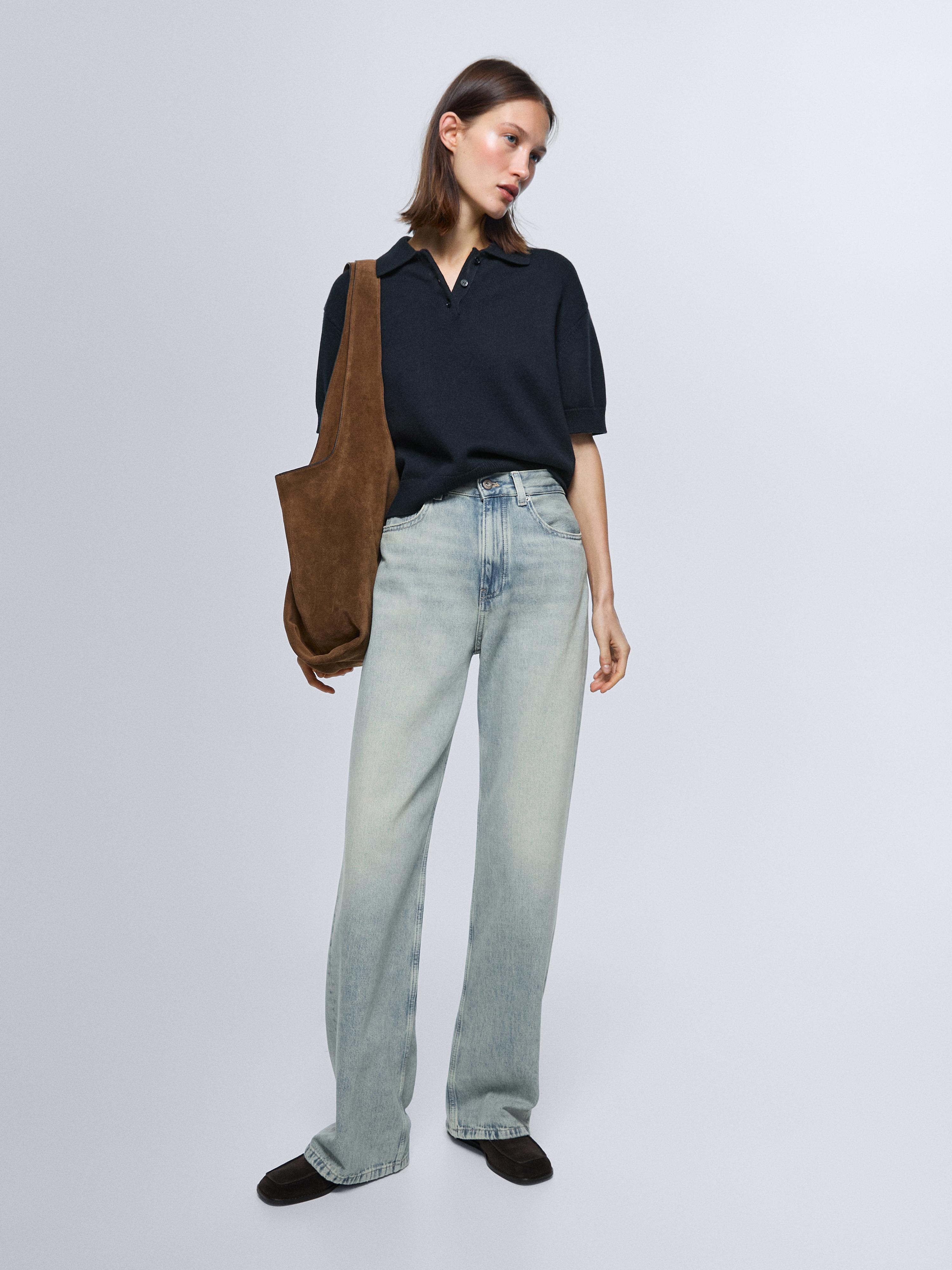 Komplet plavih traperica širokih nogavica i srednjeg struka s crnom kratkom majicom s polo ovratnikom.