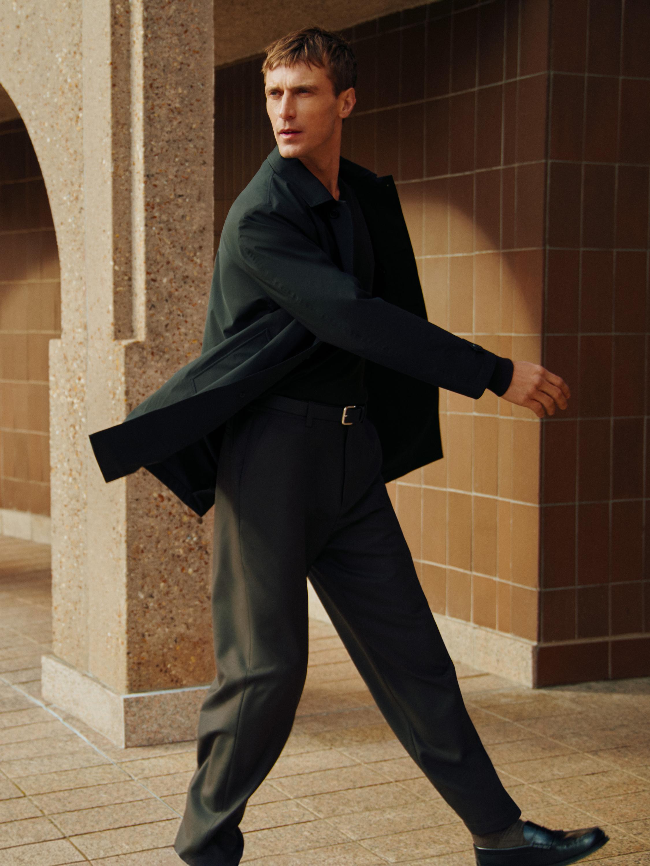 طقم يتكون من سترة باركا سوداء خفيفة وبنطال داكن مع حزام.