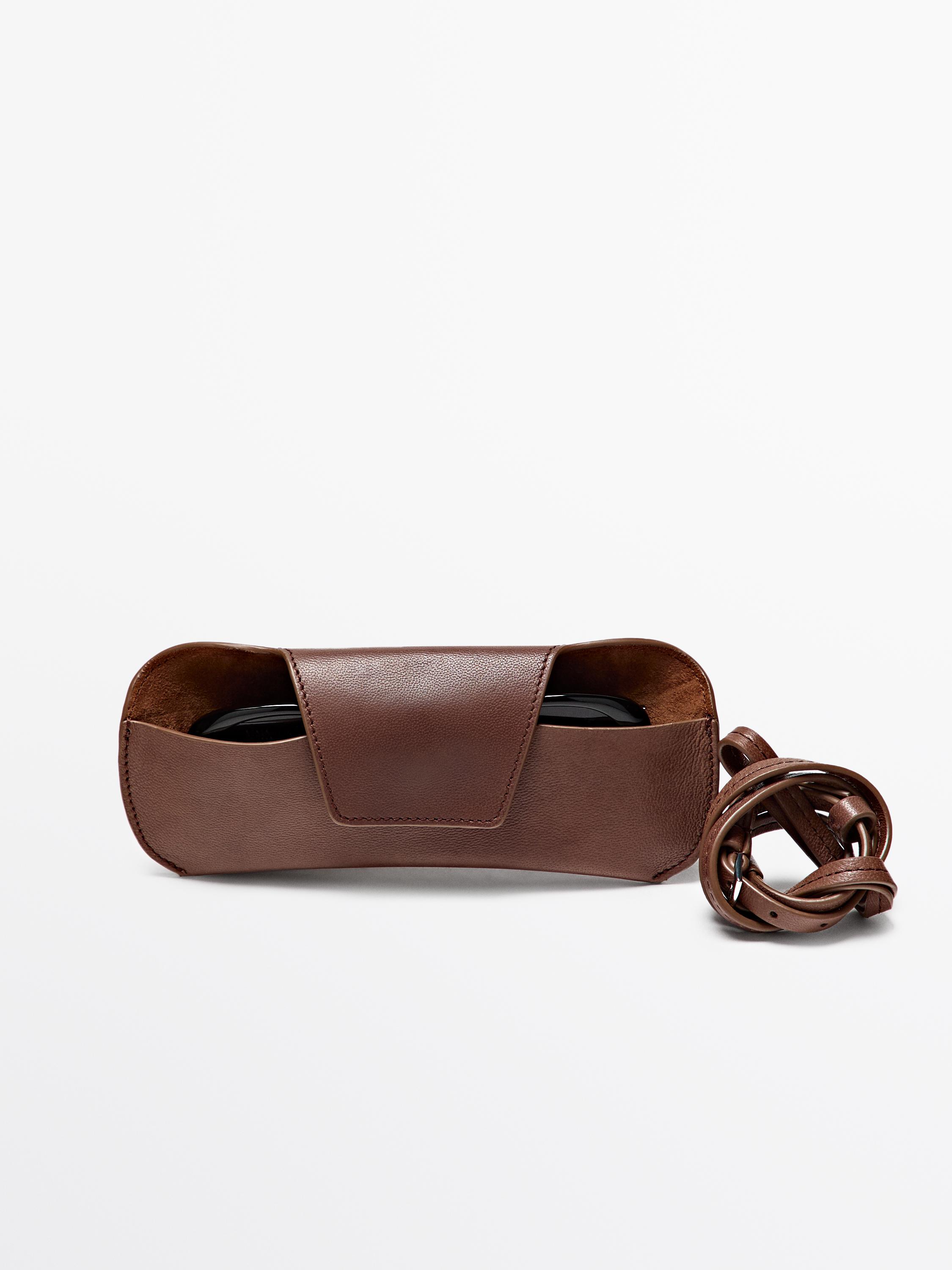 Front view of brown coin purse with flap and braided strap.