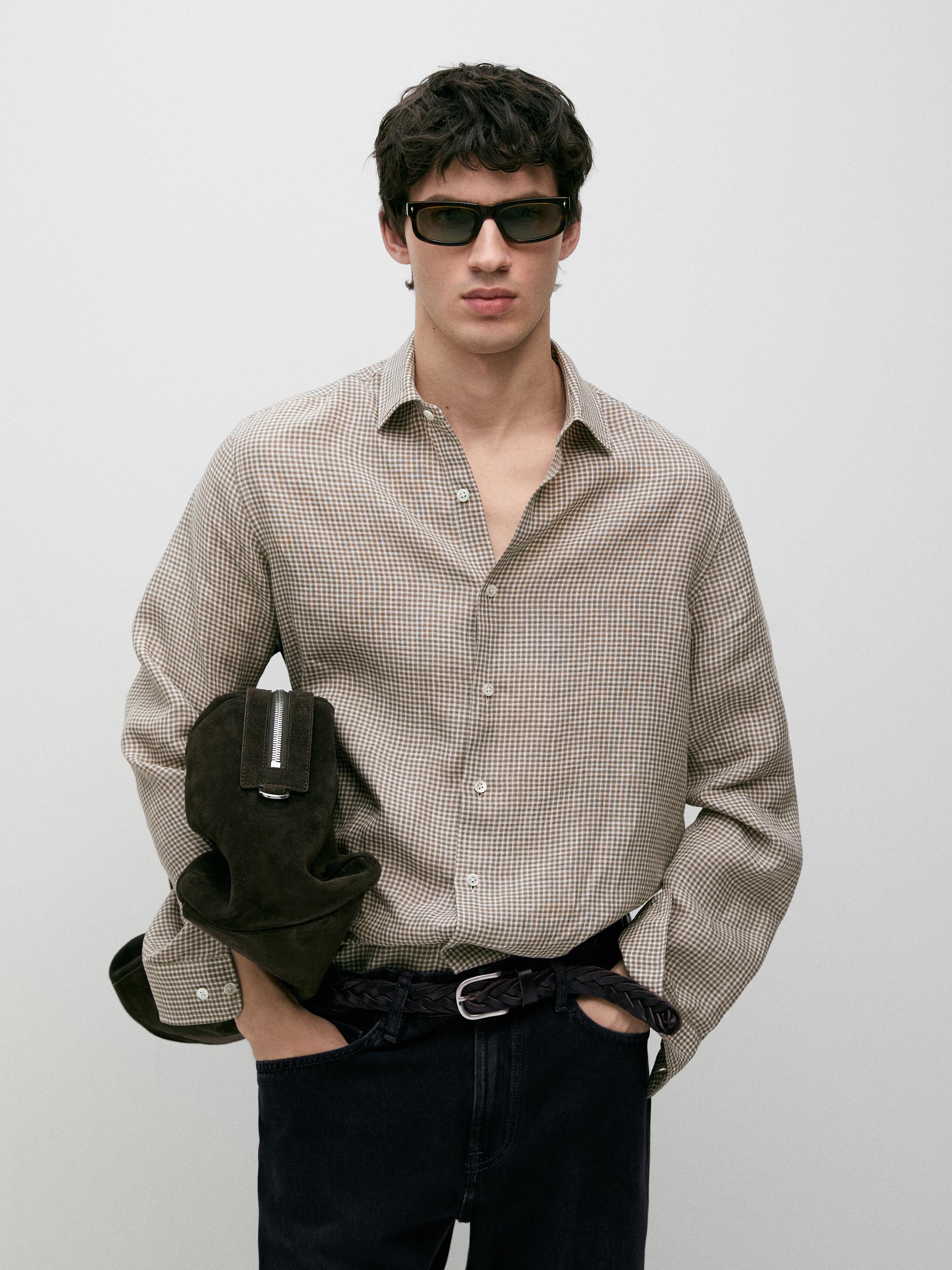 Ensemble chemise à carreaux marron à manches longues et pantalon foncé. Ceinture tressée visible.