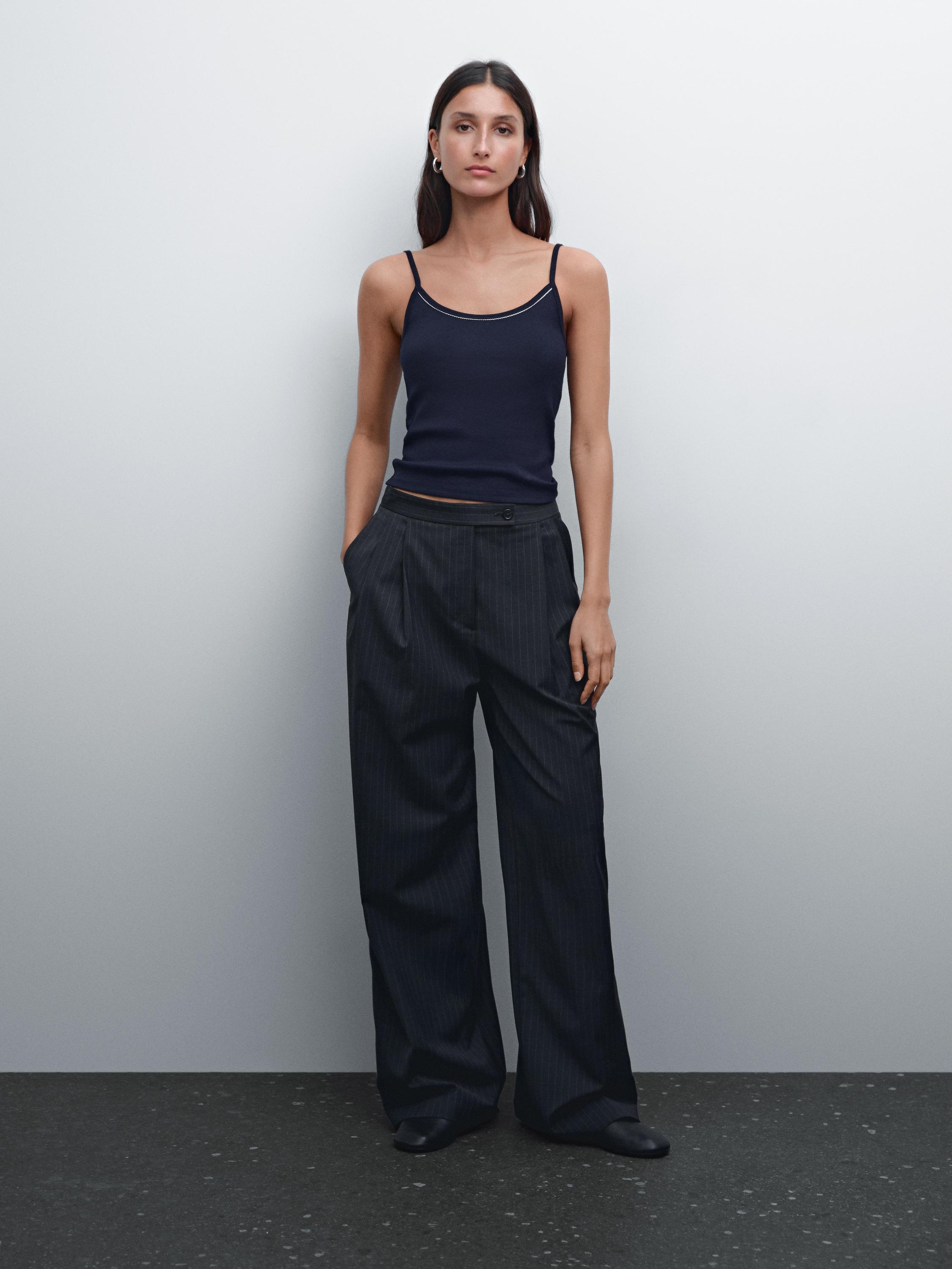 طقم مكون من توب أسود بحمالات وبنطلون واسع مخطط بخطوط داكنة مع جيوب جانبية