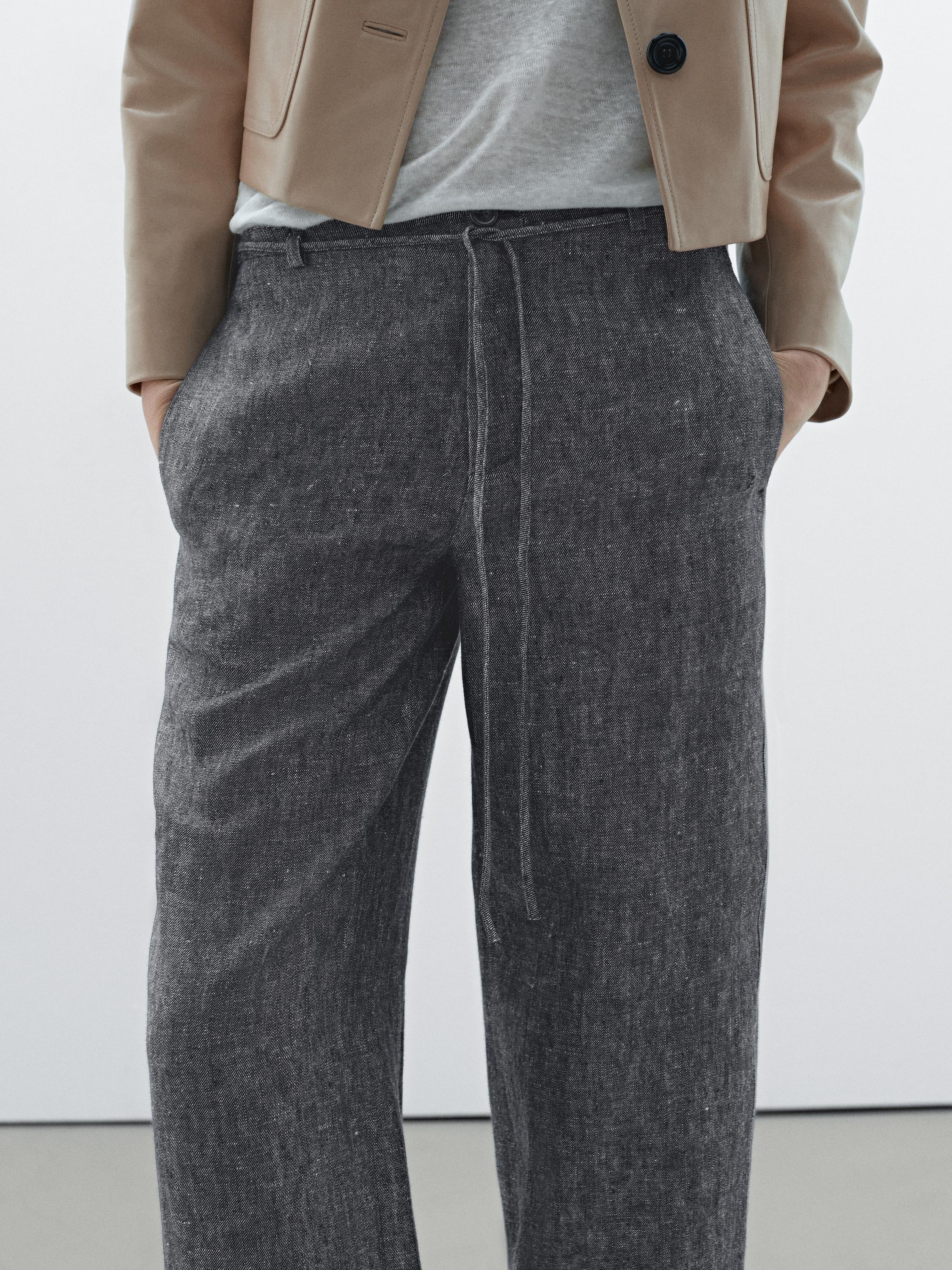 Plan moyen d'un pantalon gris foncé avec poches latérales et cordon de serrage à la taille.