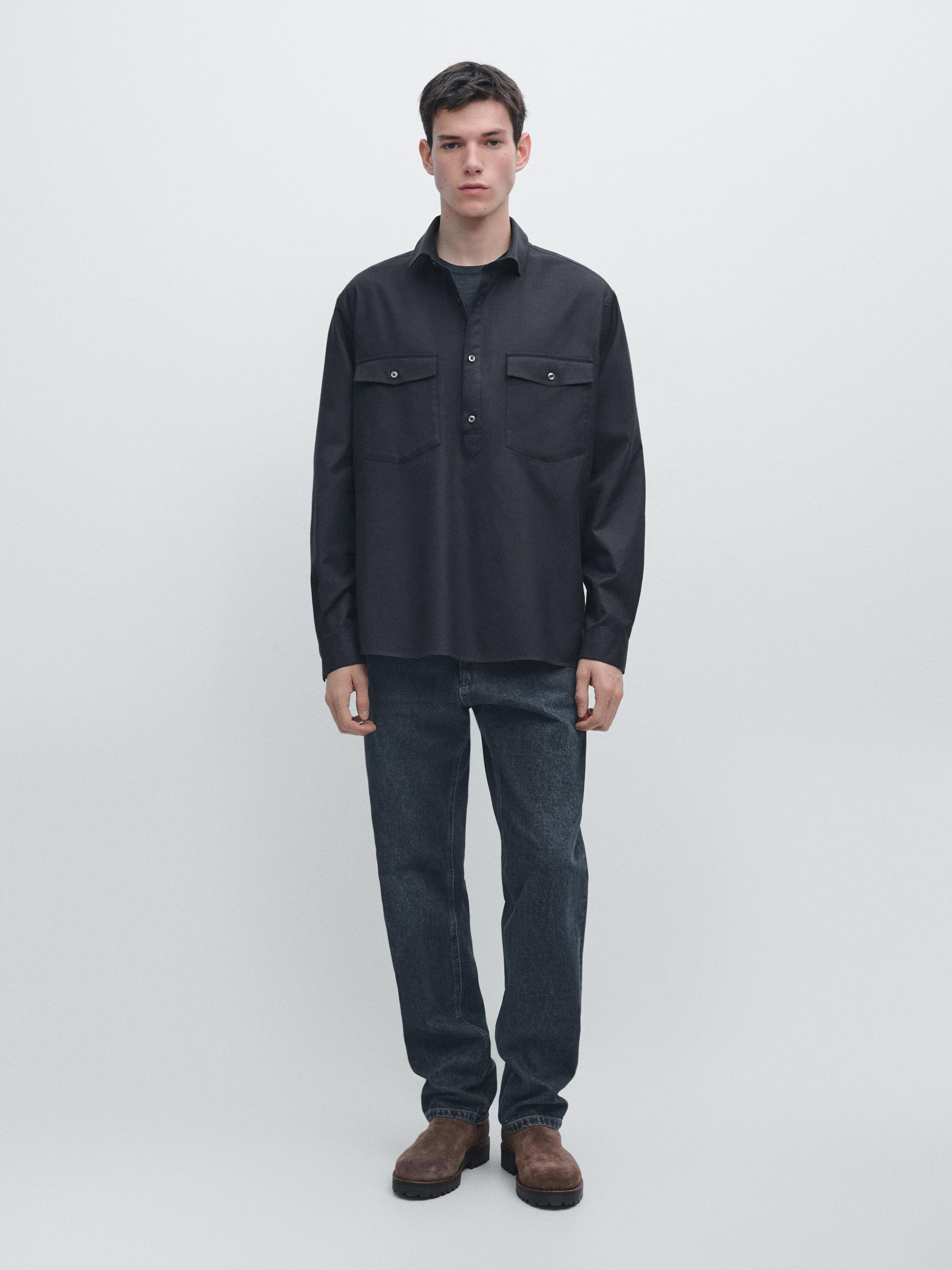 Súprava námorníckej modrej košele s dlhým rukávom s prednými vreckami a tmavých džínsov.