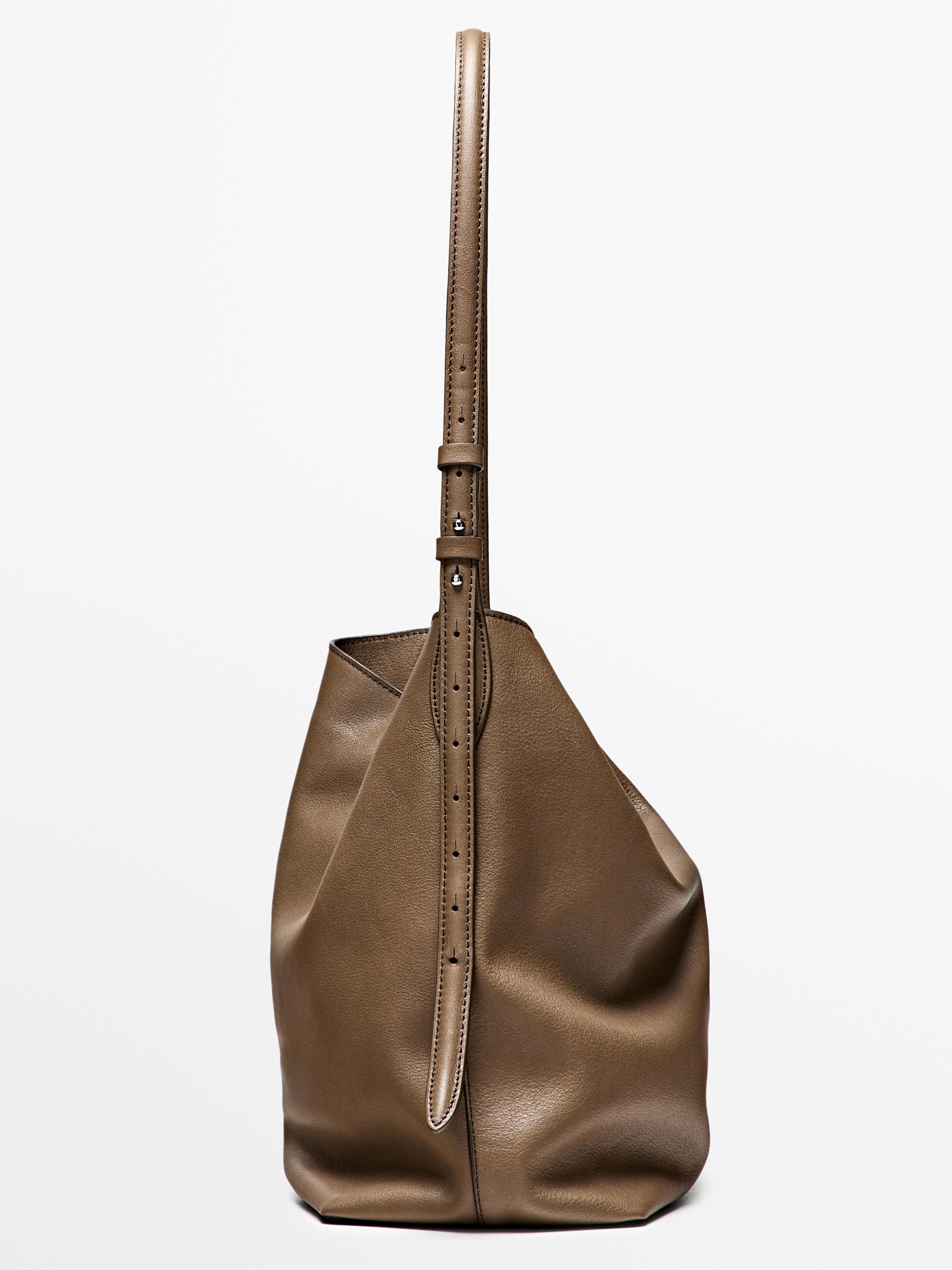 "Side view of a taupe brown handbag with an adjustable strap and minimalist design."