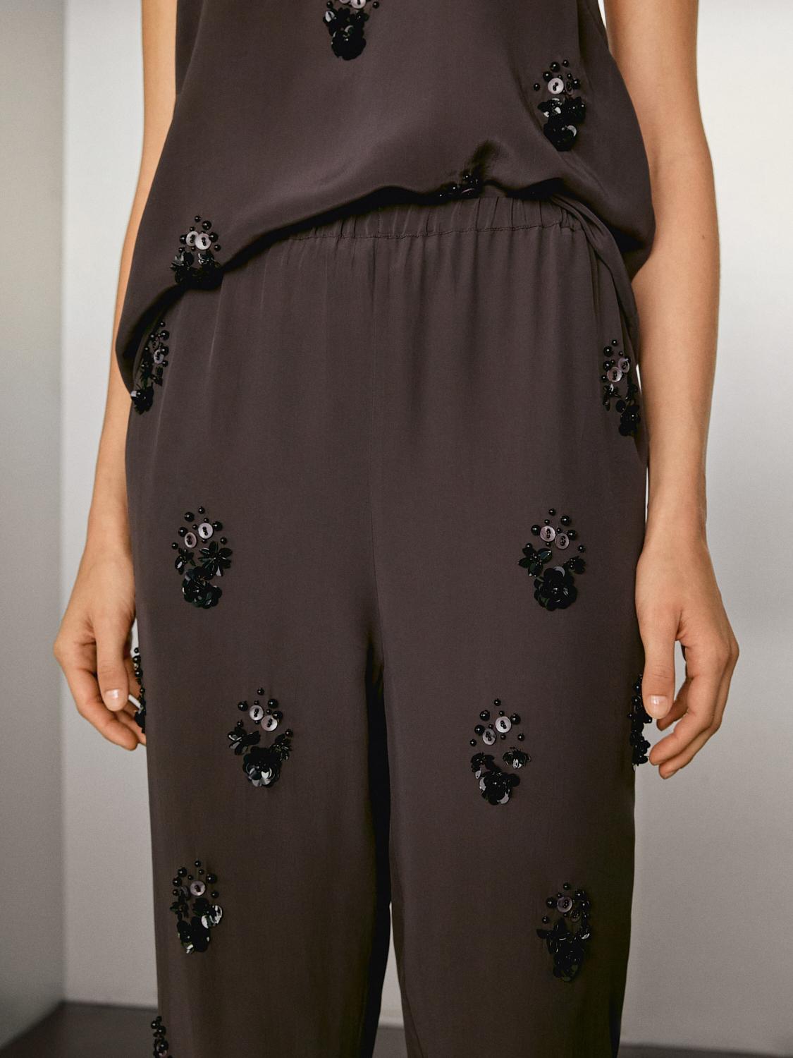 Flowing trousers with floral appliqués