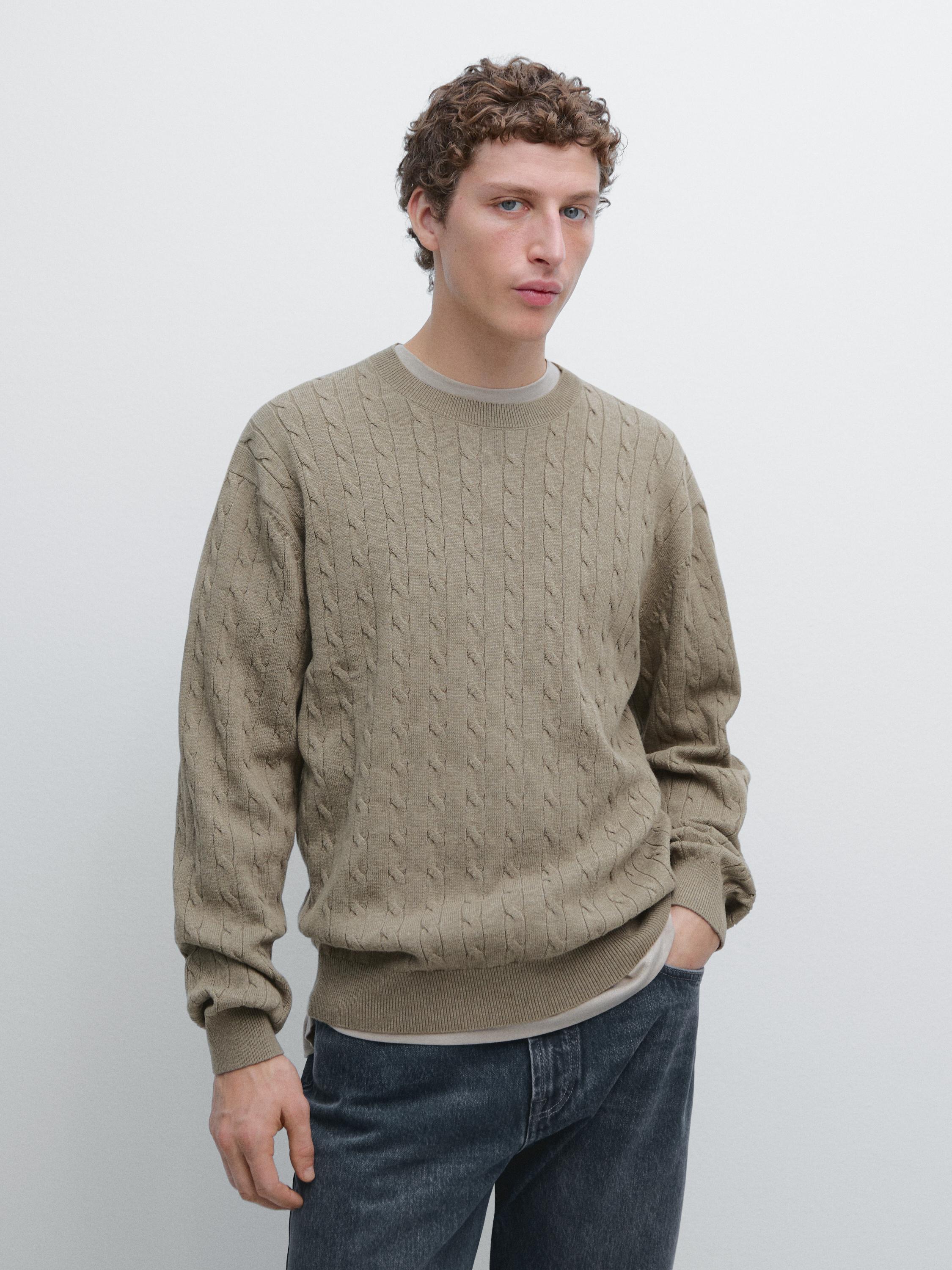 Beiges Zopfstrickpullover-Set mit Rundhalsausschnitt und dunkelblauer Jeans.