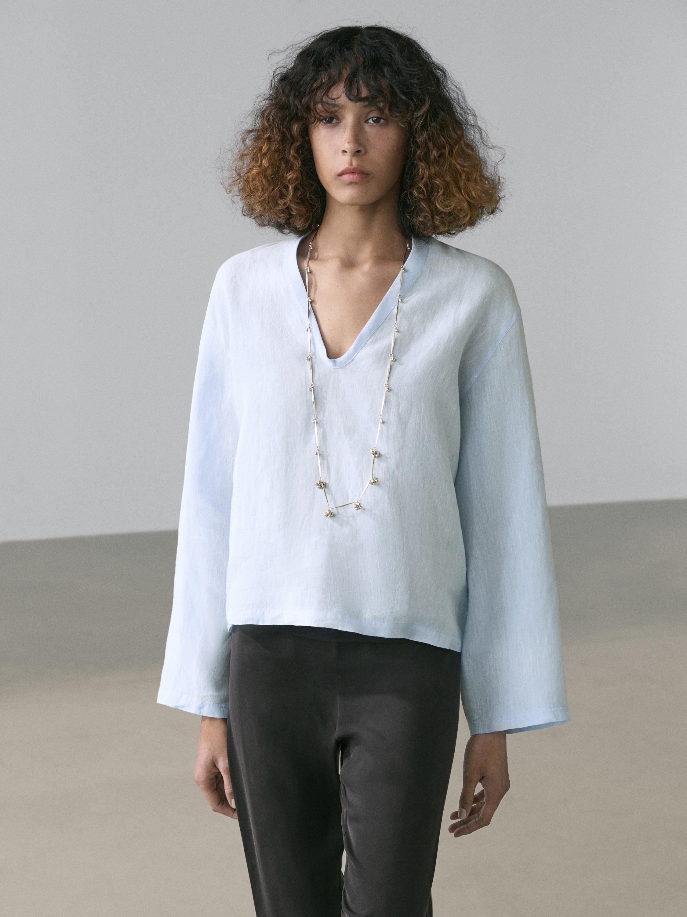 Conjunto de camisa celeste de manga larga con cuello en V y pantalones oscuros.