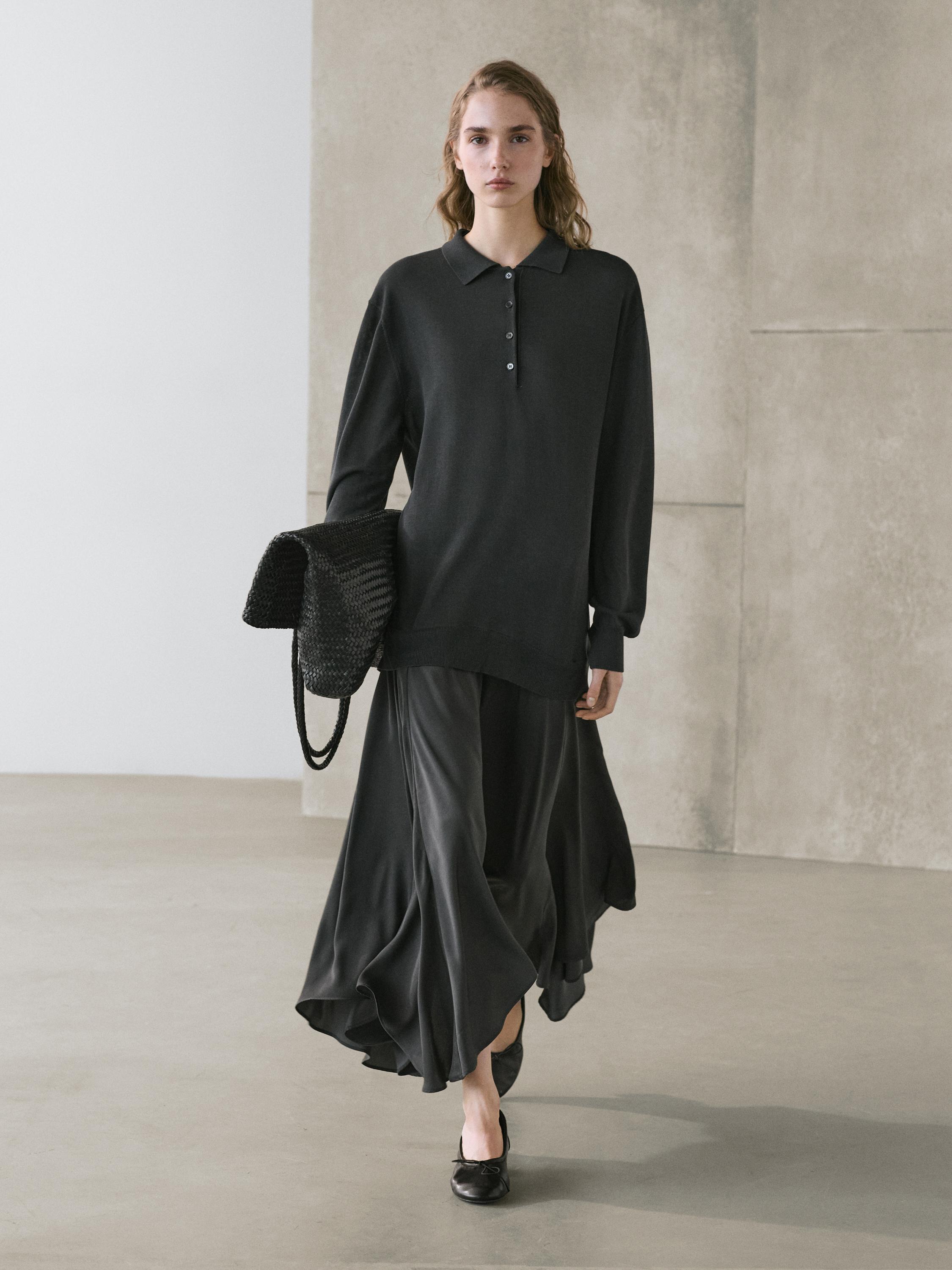Conxunto de vestido chumbo con colo polo e botóns, saia ampla e longa, bolso tecido negro, zapatos negros.