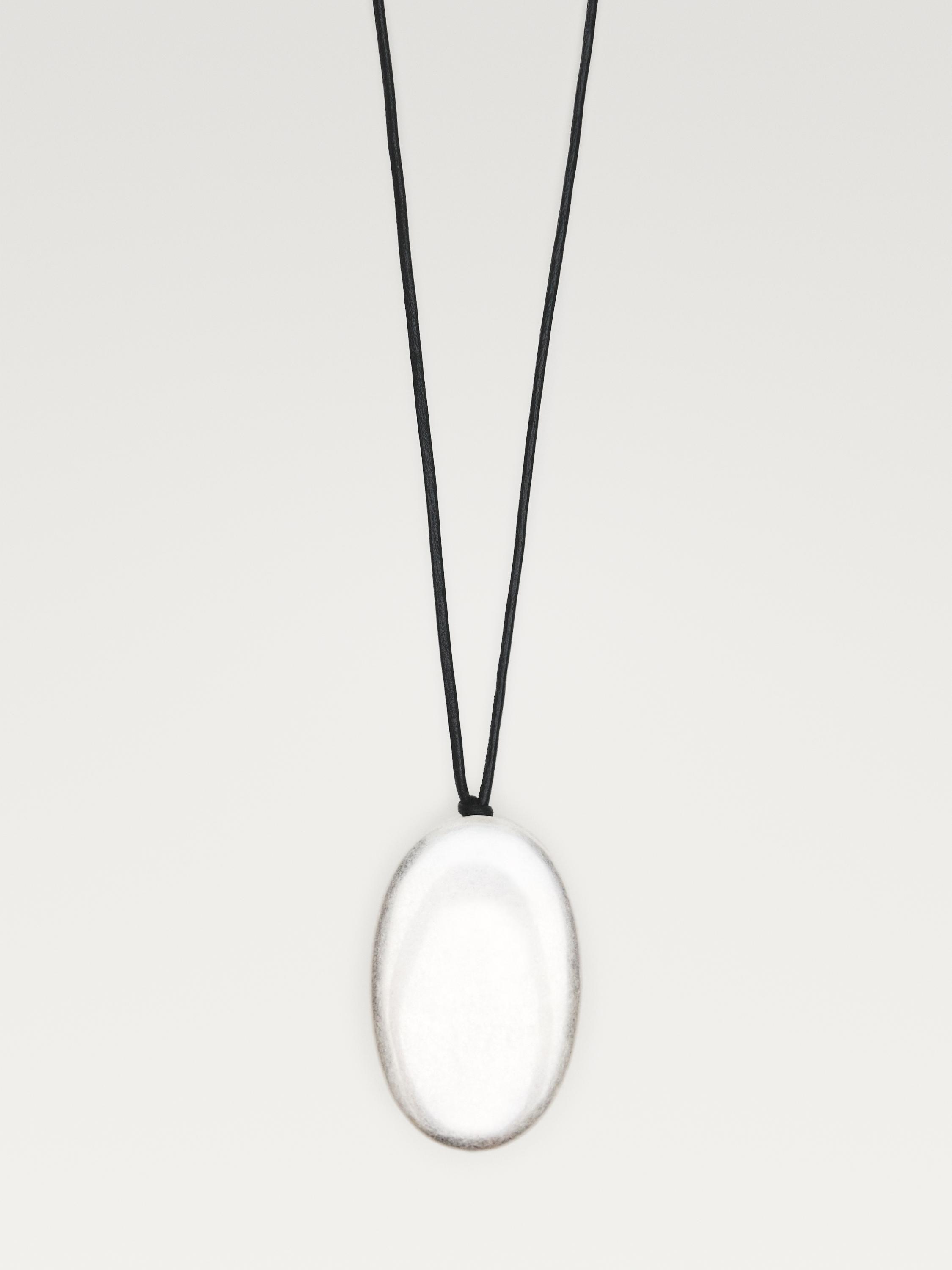 Halskjede med ovalt sølvfarget anheng og svart snor.