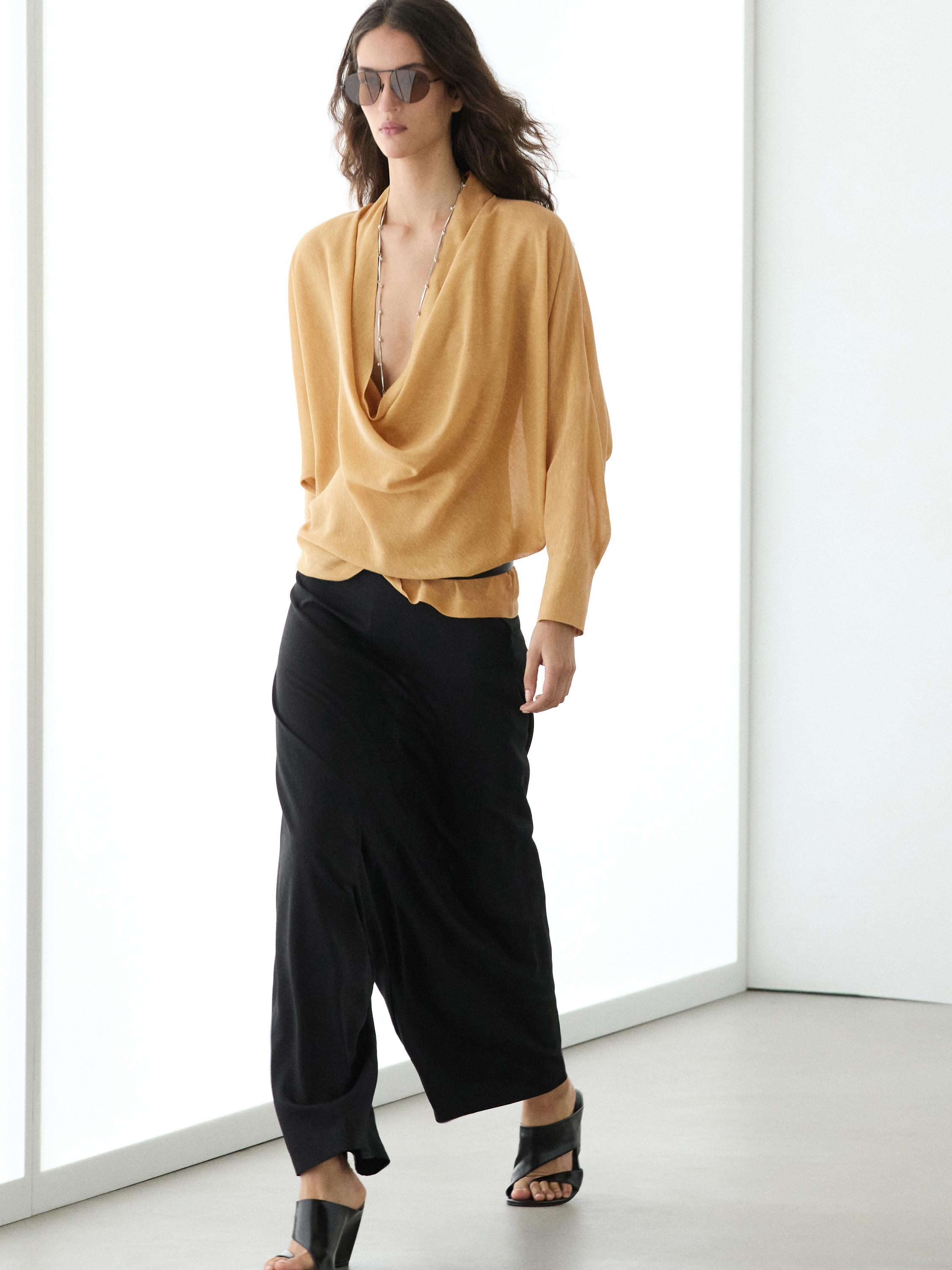 Ensemble blouse jaune moutarde à col bénitier et pantalon noir ample.