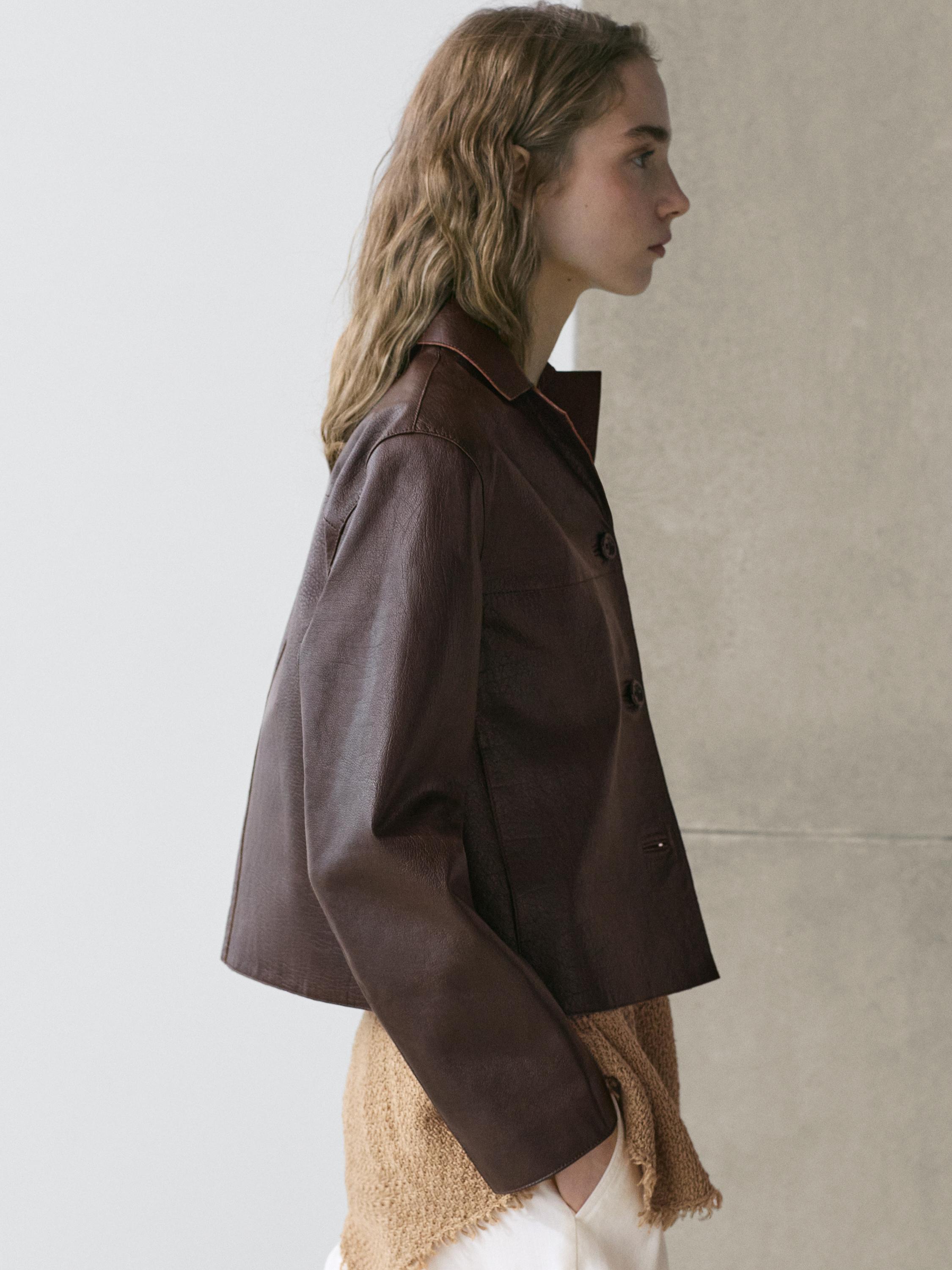 Plano medio de chaqueta corta marrón con botones y cuello clásico.