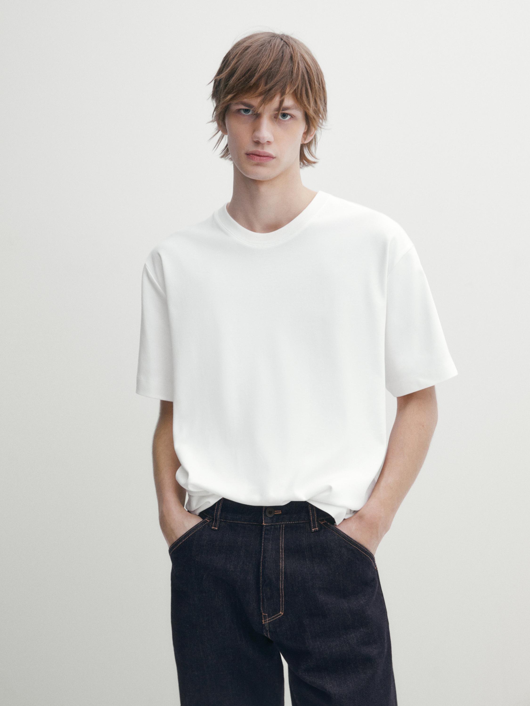 طقم يتكون من تي شيرت أبيض بأكمام قصيرة وبنطلون جينز أزرق داكن مع جيوب أمامية ظاهرة.