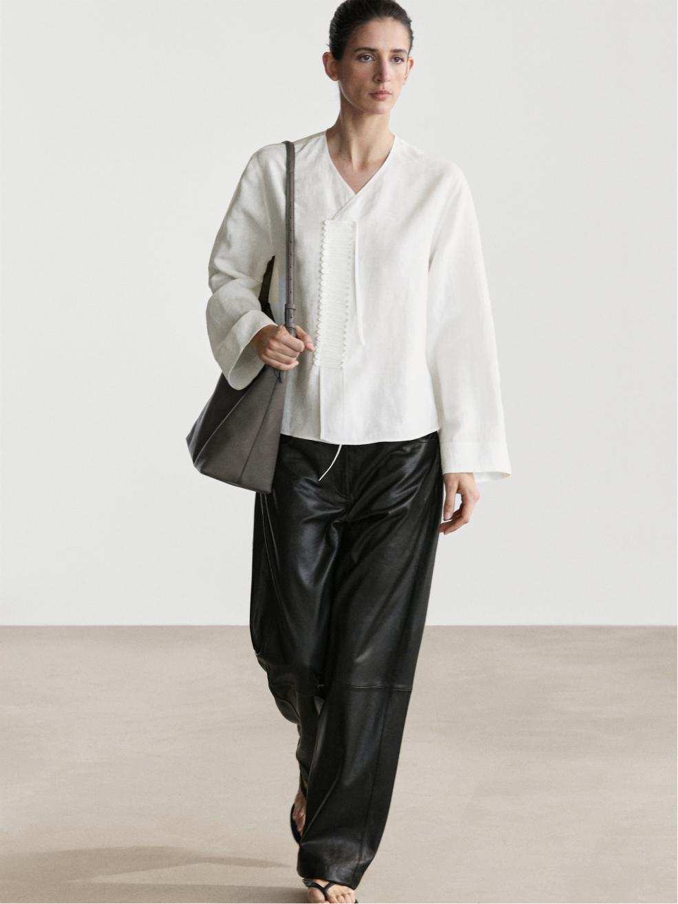 Conjunto de camisa blanca fluida con detalle en pechera y pantalones negros anchos.