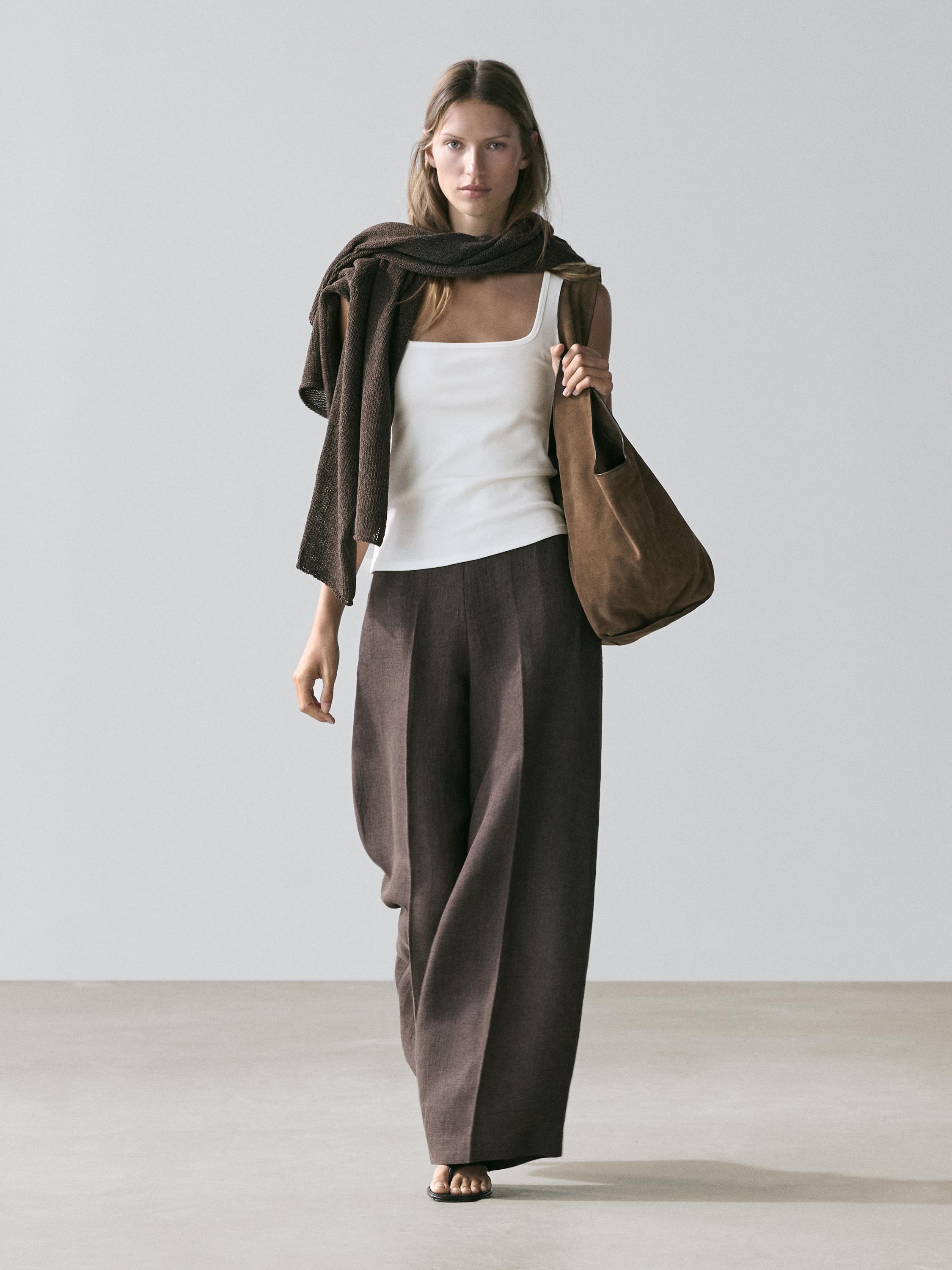 طقم توب أبيض مائل للصفرة بياقة مربعة وبنطال بني واسع. وشاح بني وحقيبة بنية.