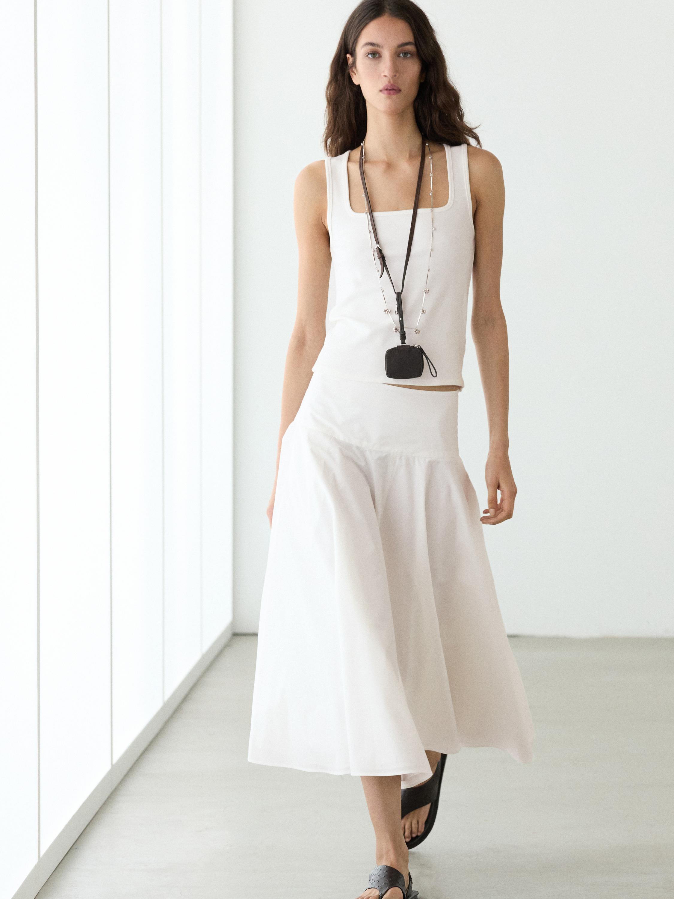 White midi skirt set with yoke and white sleeveless top.