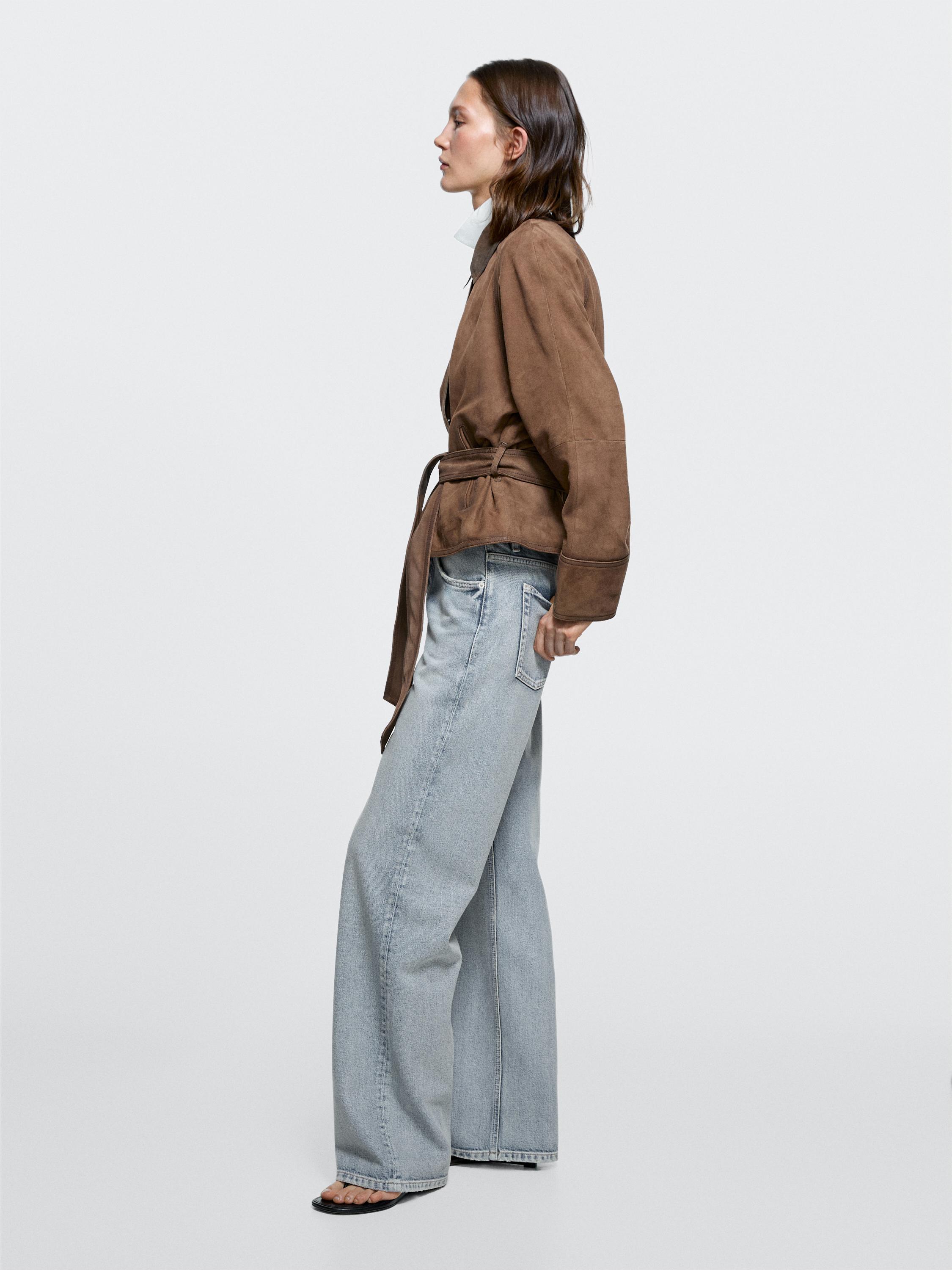 Conxunto de chaqueta marrón con cinto e vaqueiros azul claro de perna ancha e tiro medio.