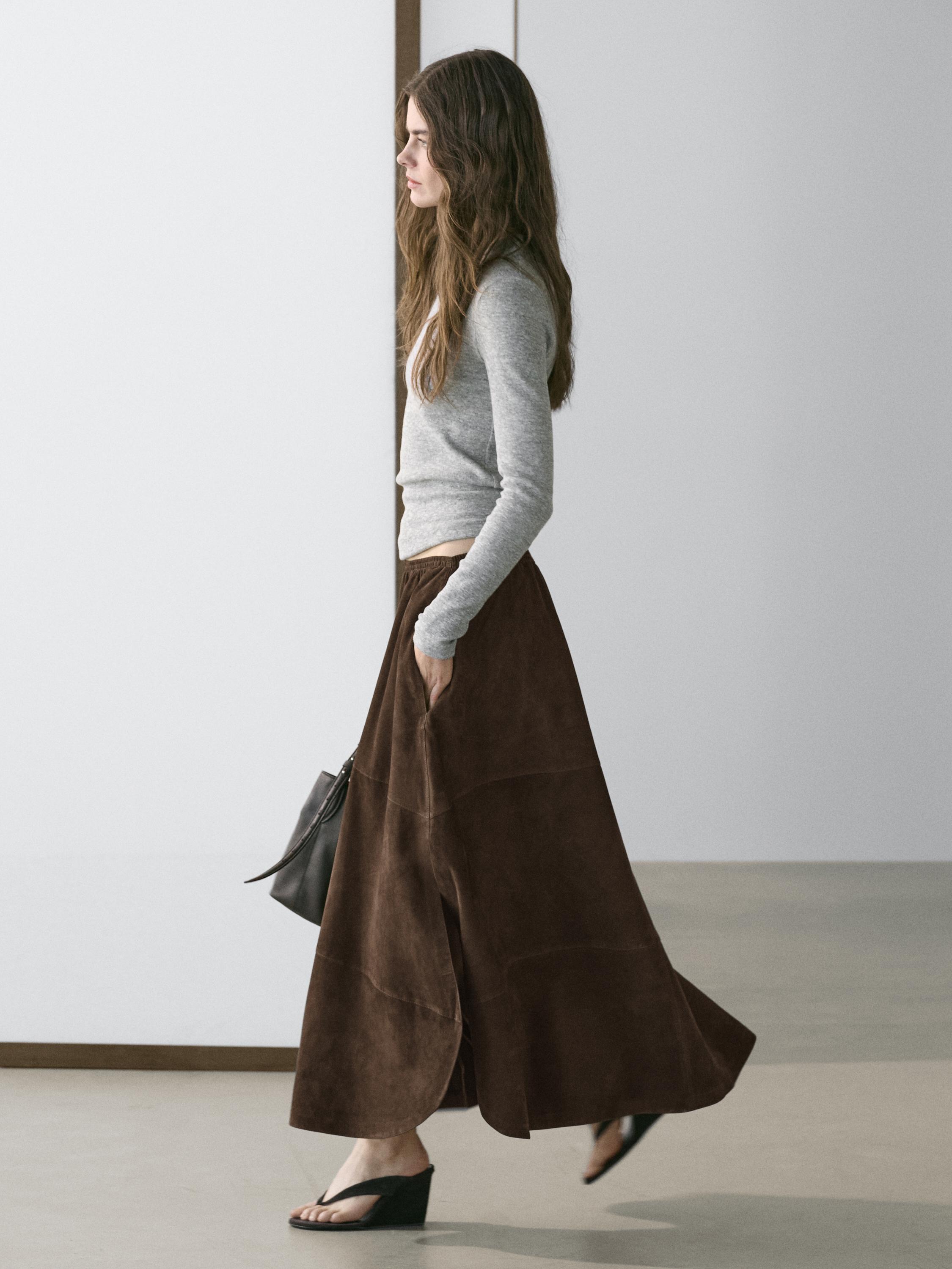 Midi-rokset in bruin met zijzakken en grijze trui met lange mouwen.
