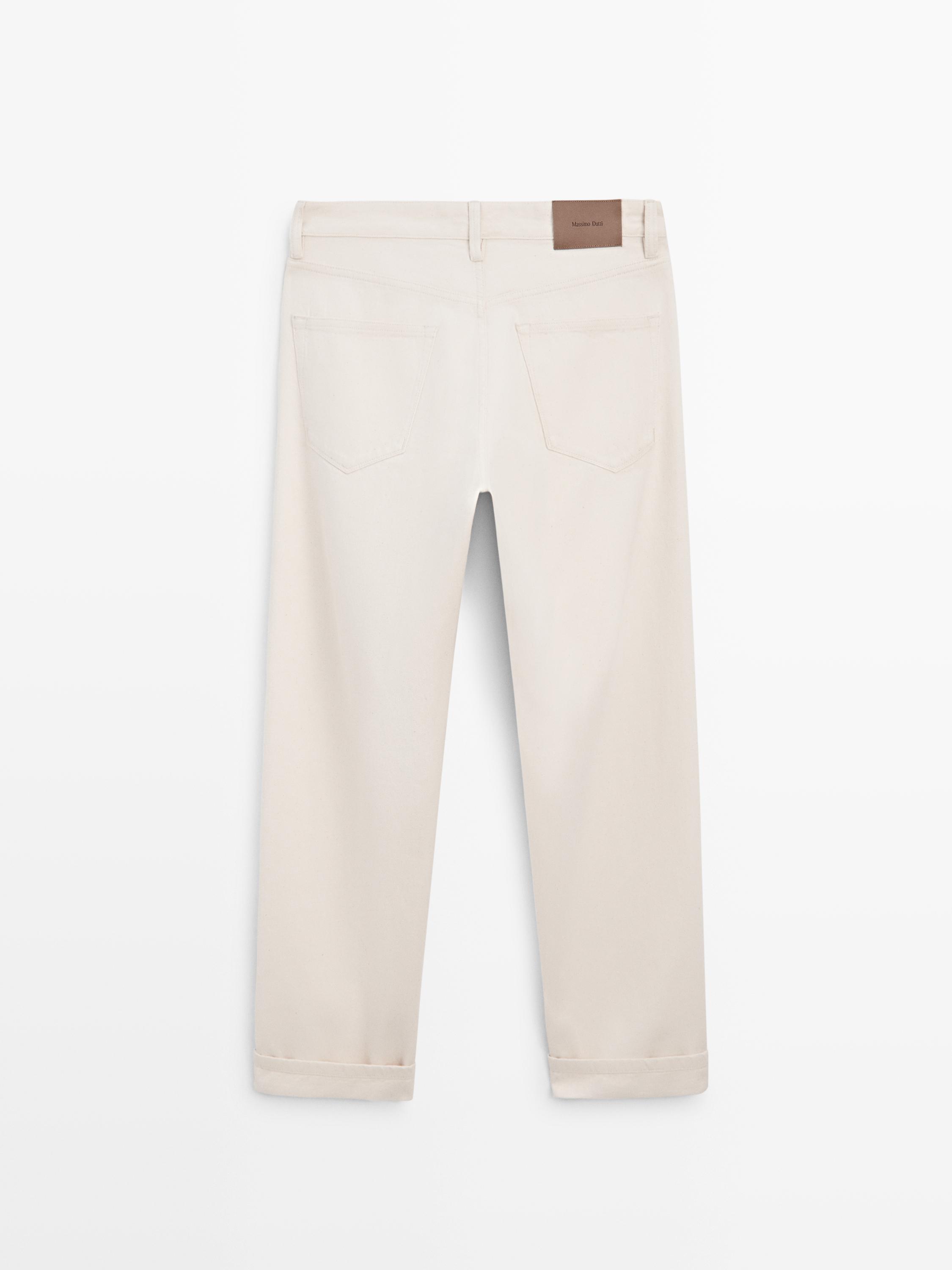 Back view of raw denim jeans with back pockets and brown label at the waist.