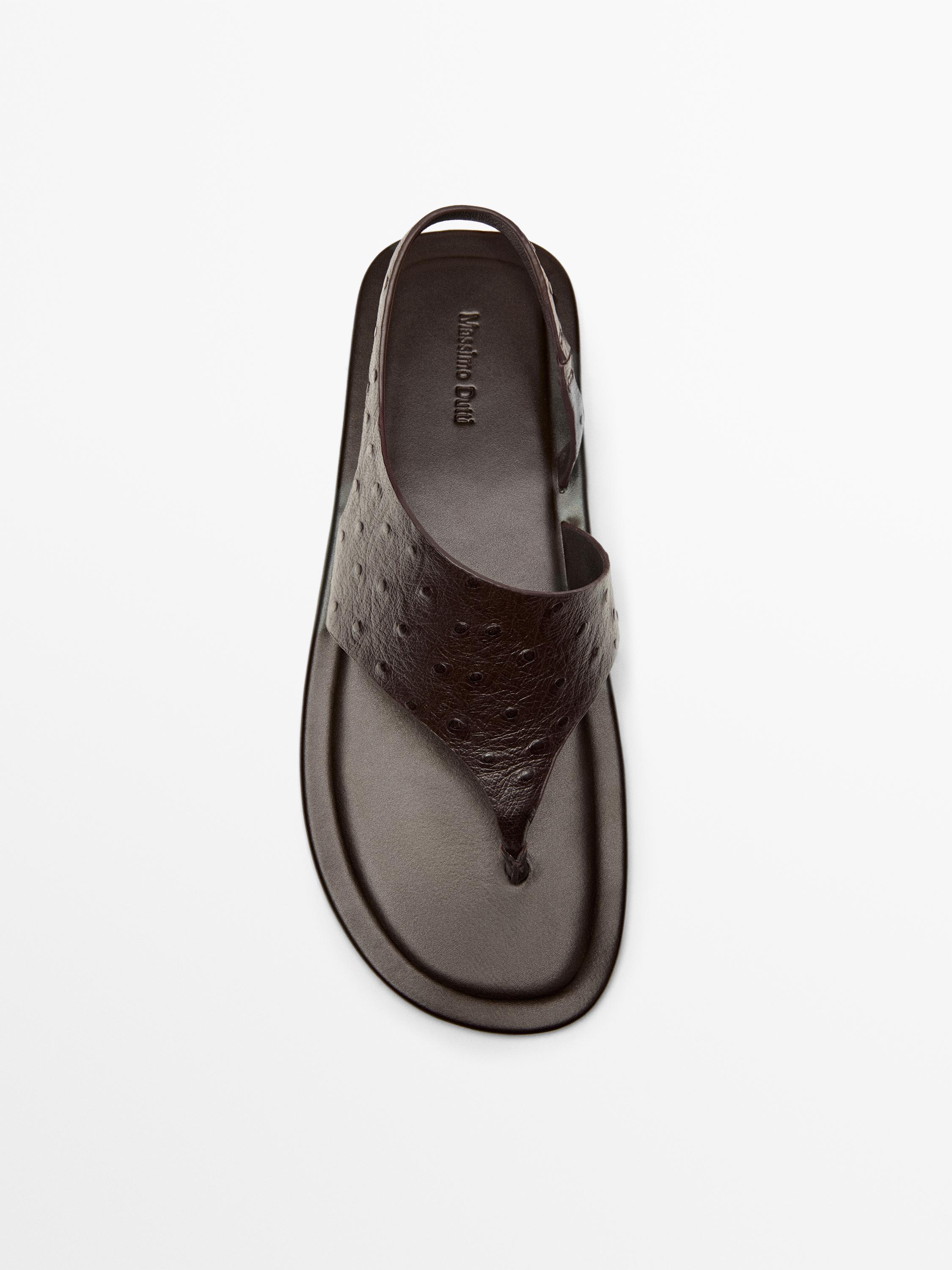 Bovenaanzicht van een bruine platte sandaal met dierenprint en een achterbandje. Zichtbare tekst: "Massimo Dutti".