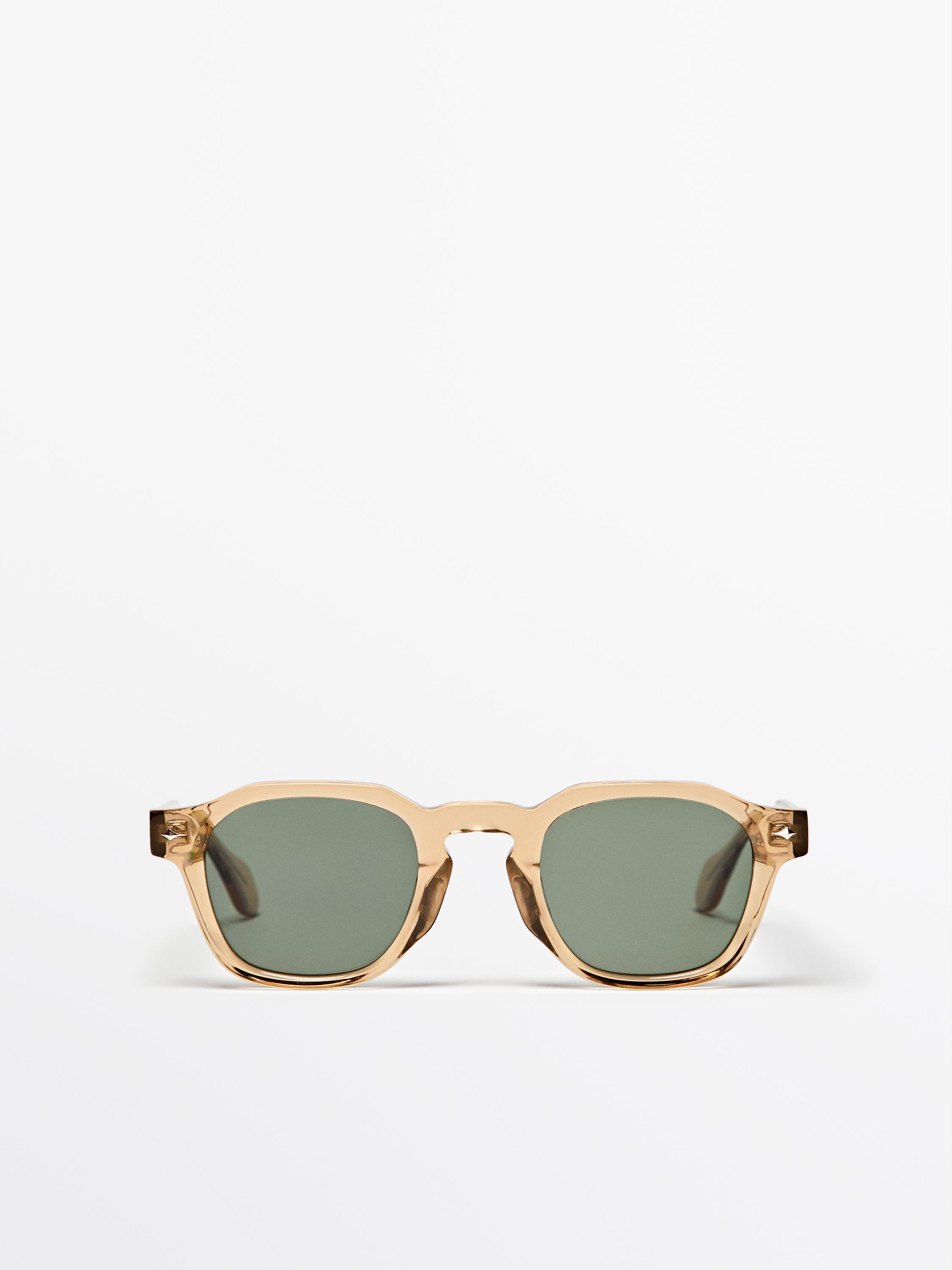 Vista frontal d'ulleres de sol mostassa amb muntura quadrada i lents fosques.