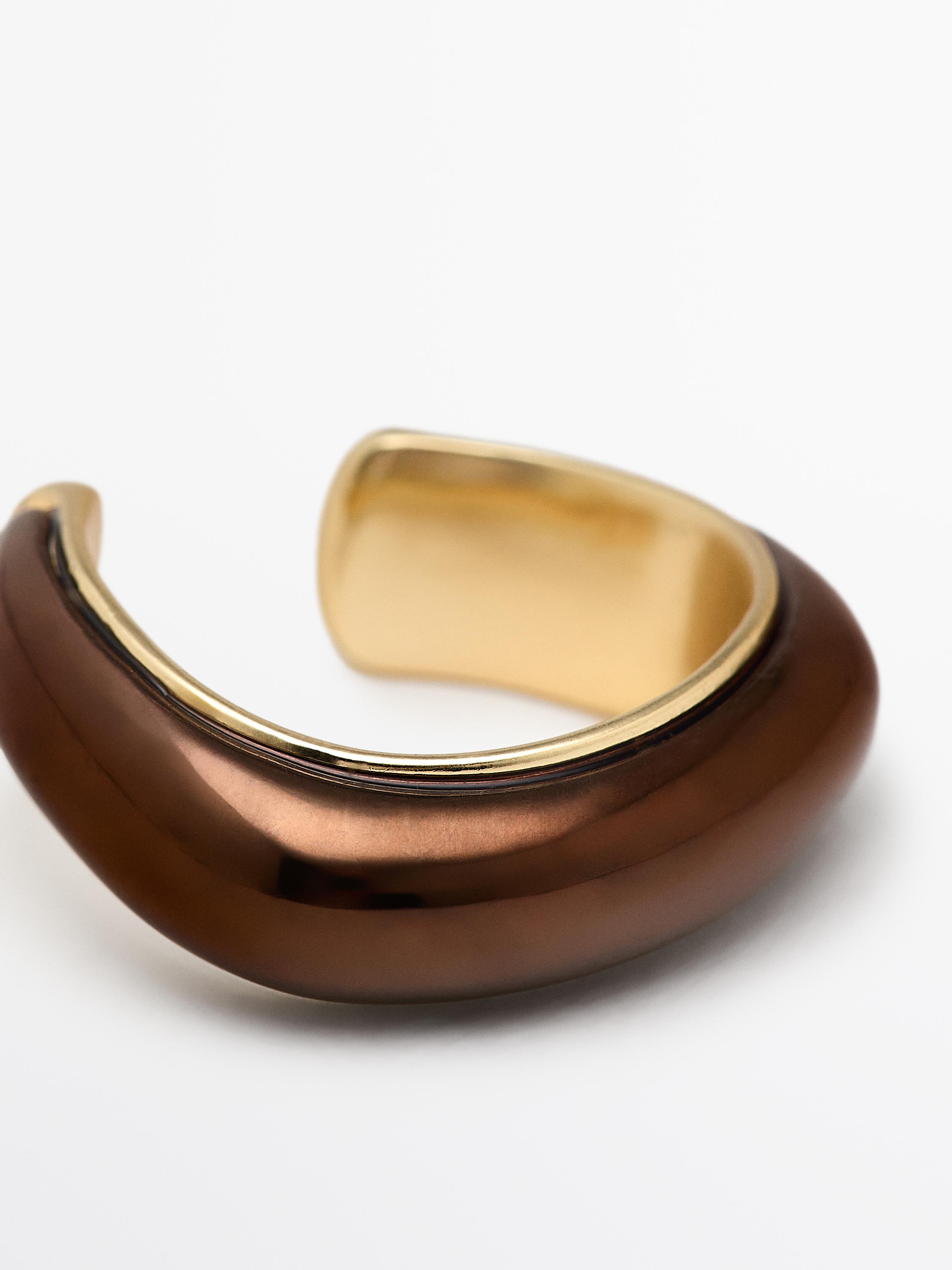 Close-up of a golden enameled ring with a glossy finish and open design.