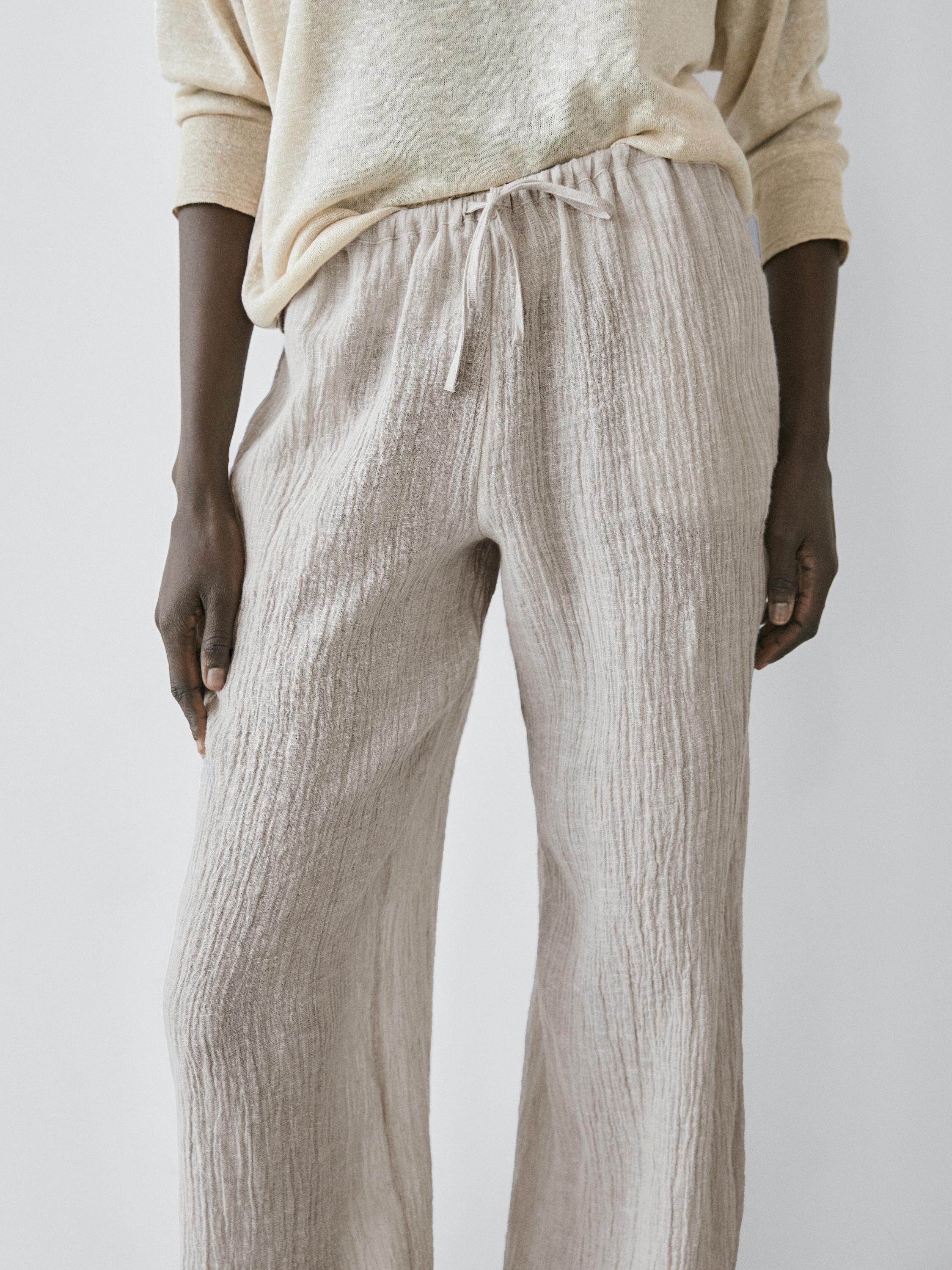 Esnek bel ve ayarlanabilir kordonlu kum rengi pantolonun orta çekimi.