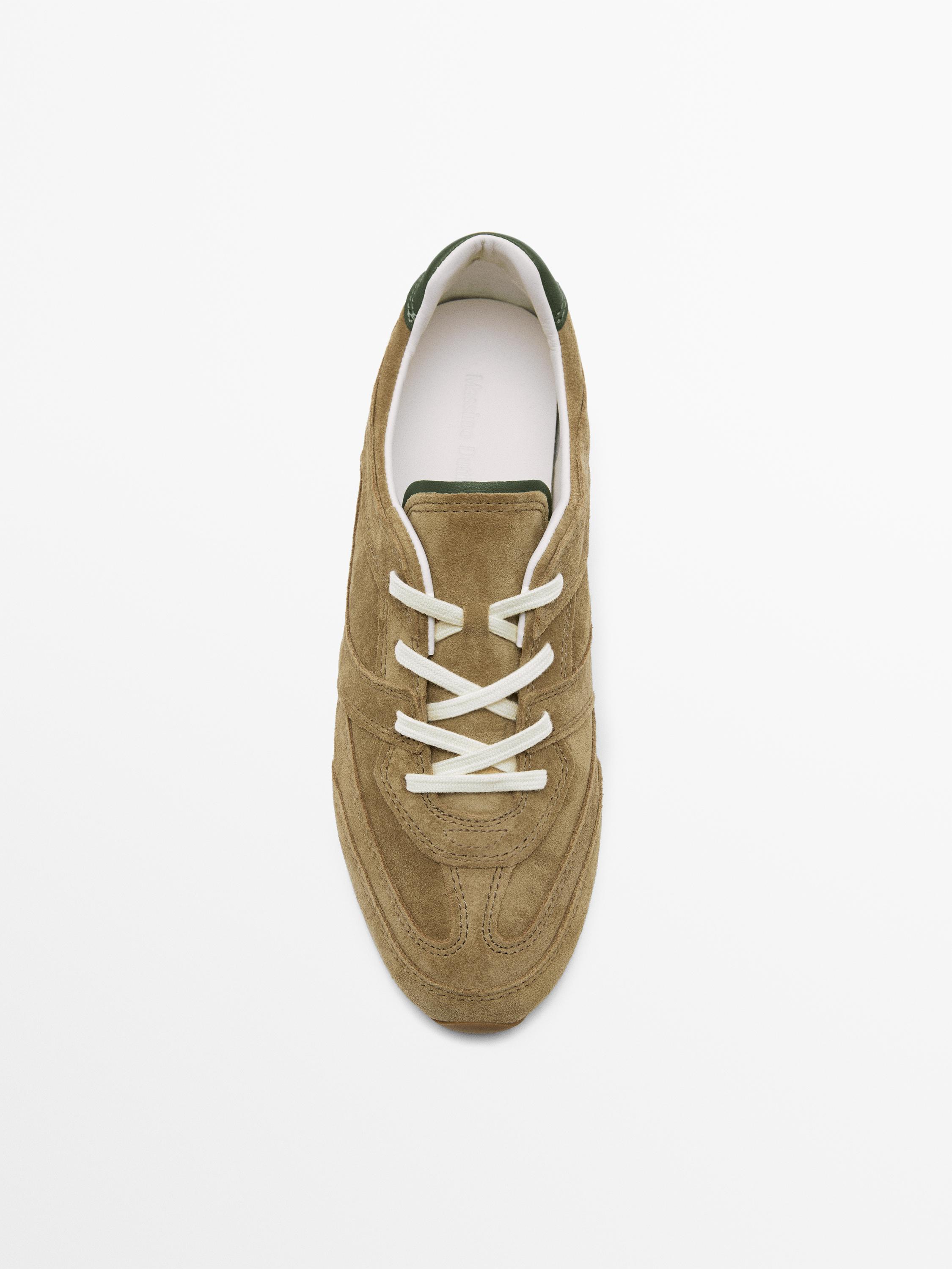 Top view of a brown sneaker with white laces and dark green details.