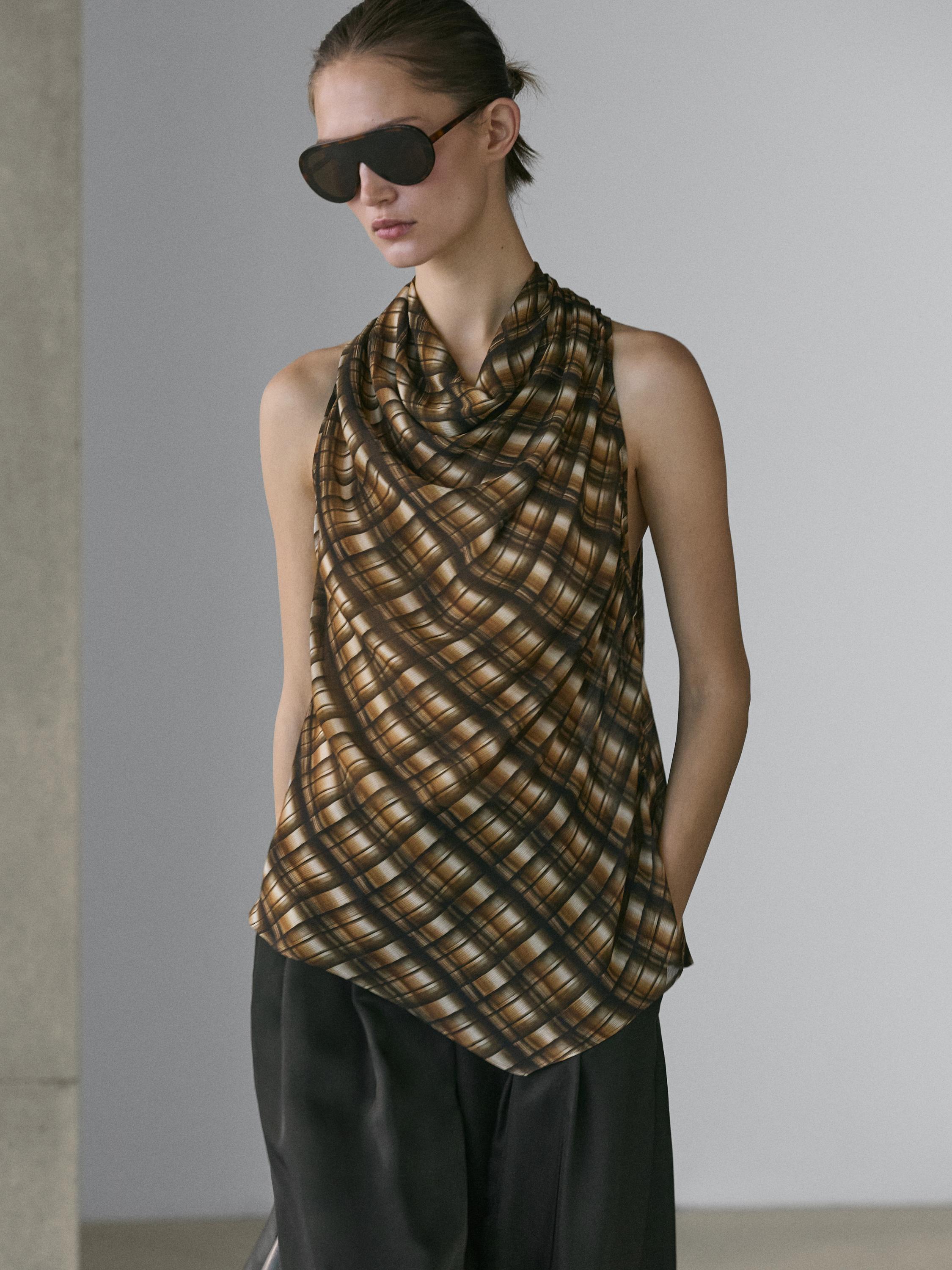 Средний план топа без рукавов с клетчатым принтом в коричневых тонах и драпированным воротником.