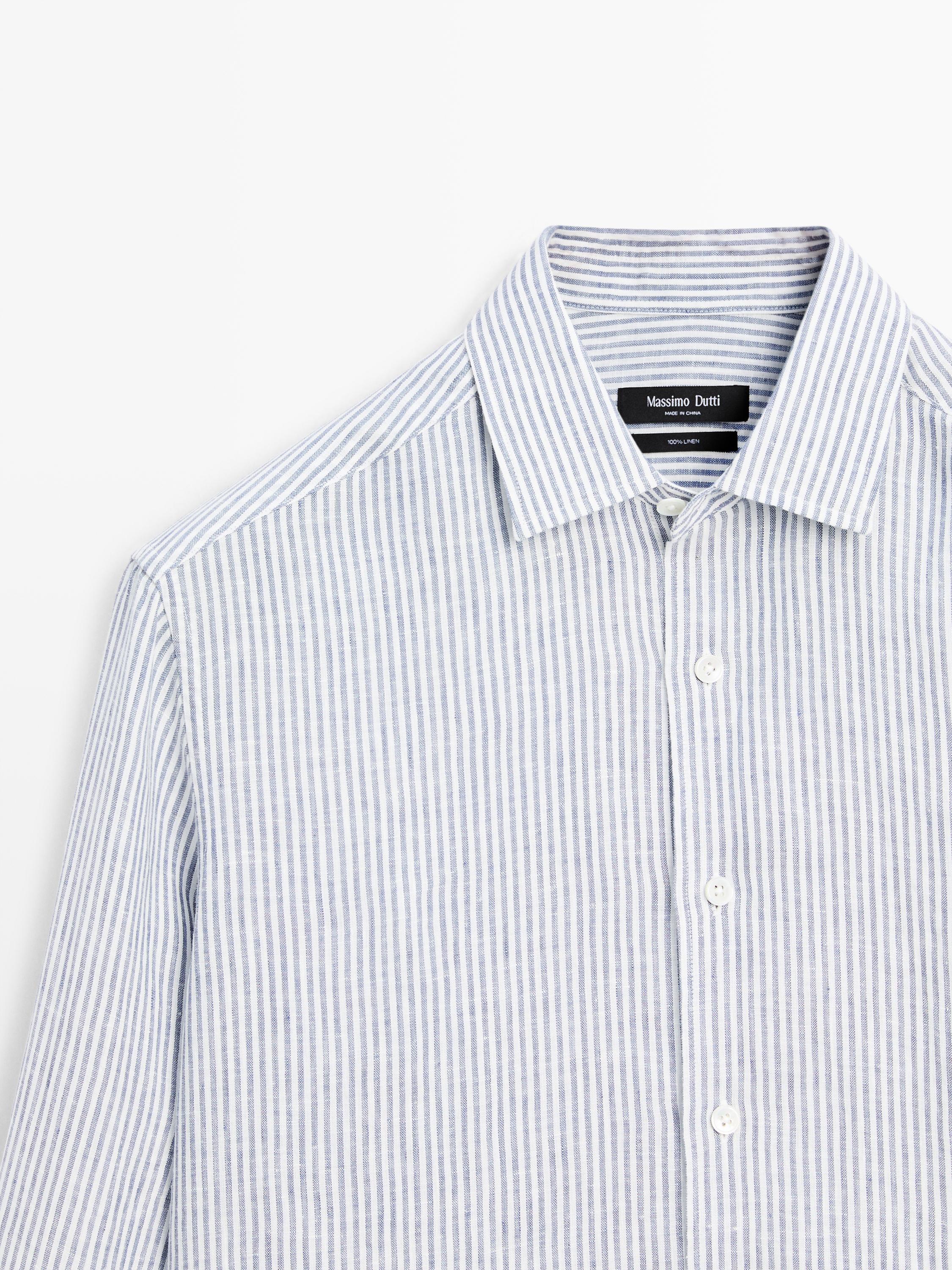 Plano medio de camisa azul de rayas con cuello clásico y botonadura frontal.