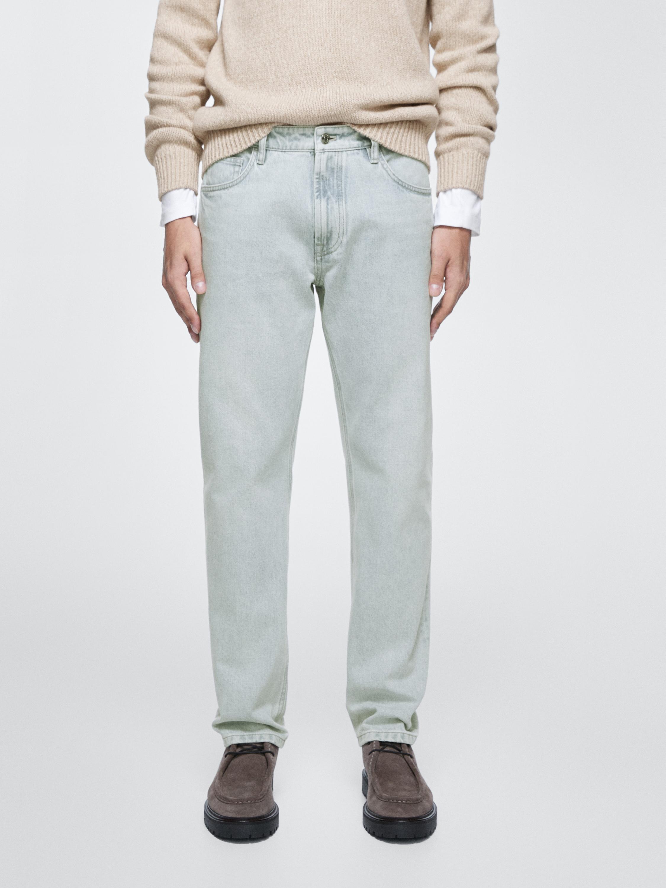 Conjunto de jeans azul claro tapered fit con bolsillos laterales y traseros, y suéter beige.