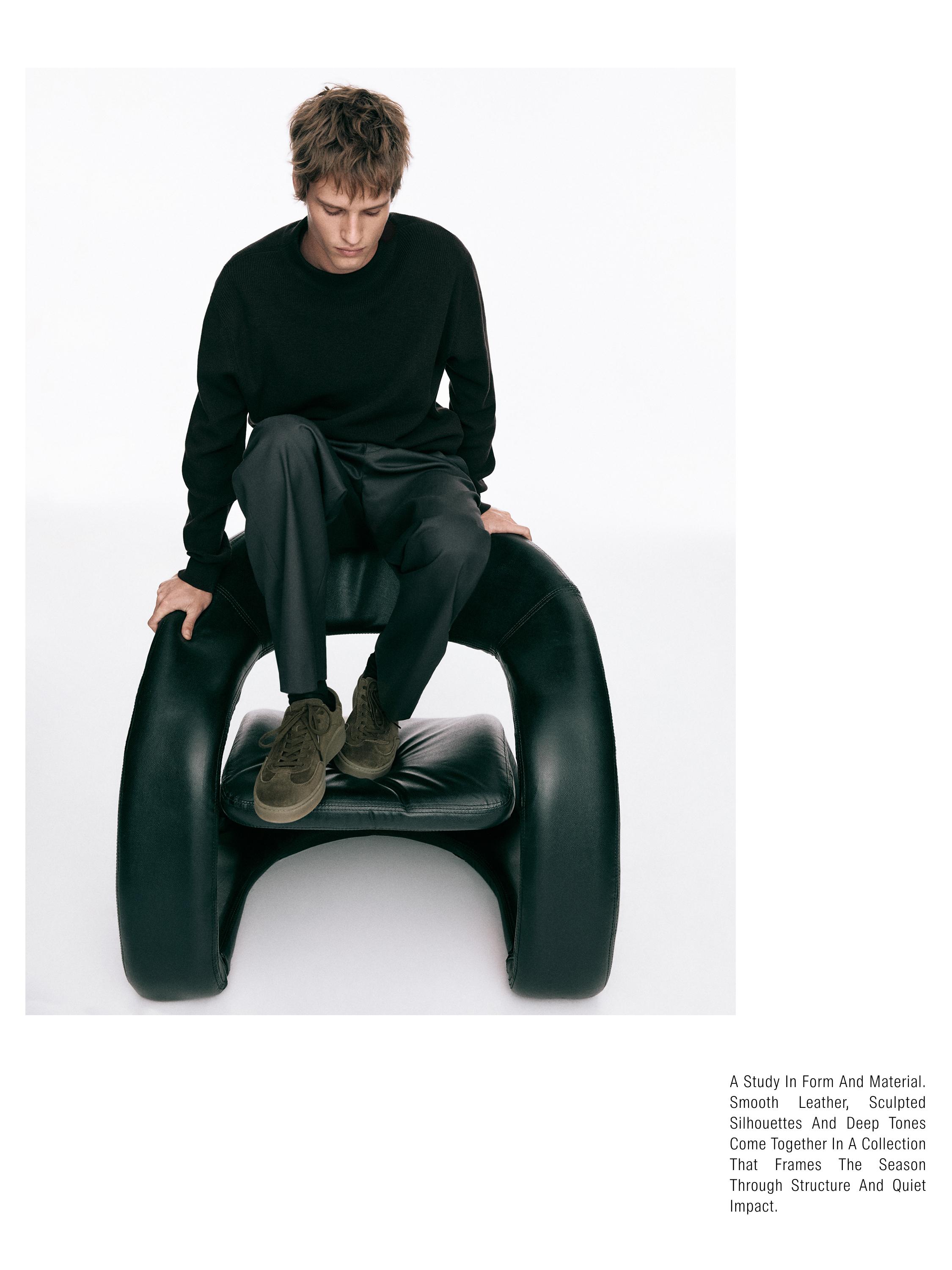 Set me triko të zi dhe pantallona të errëta, me atlete kafe.