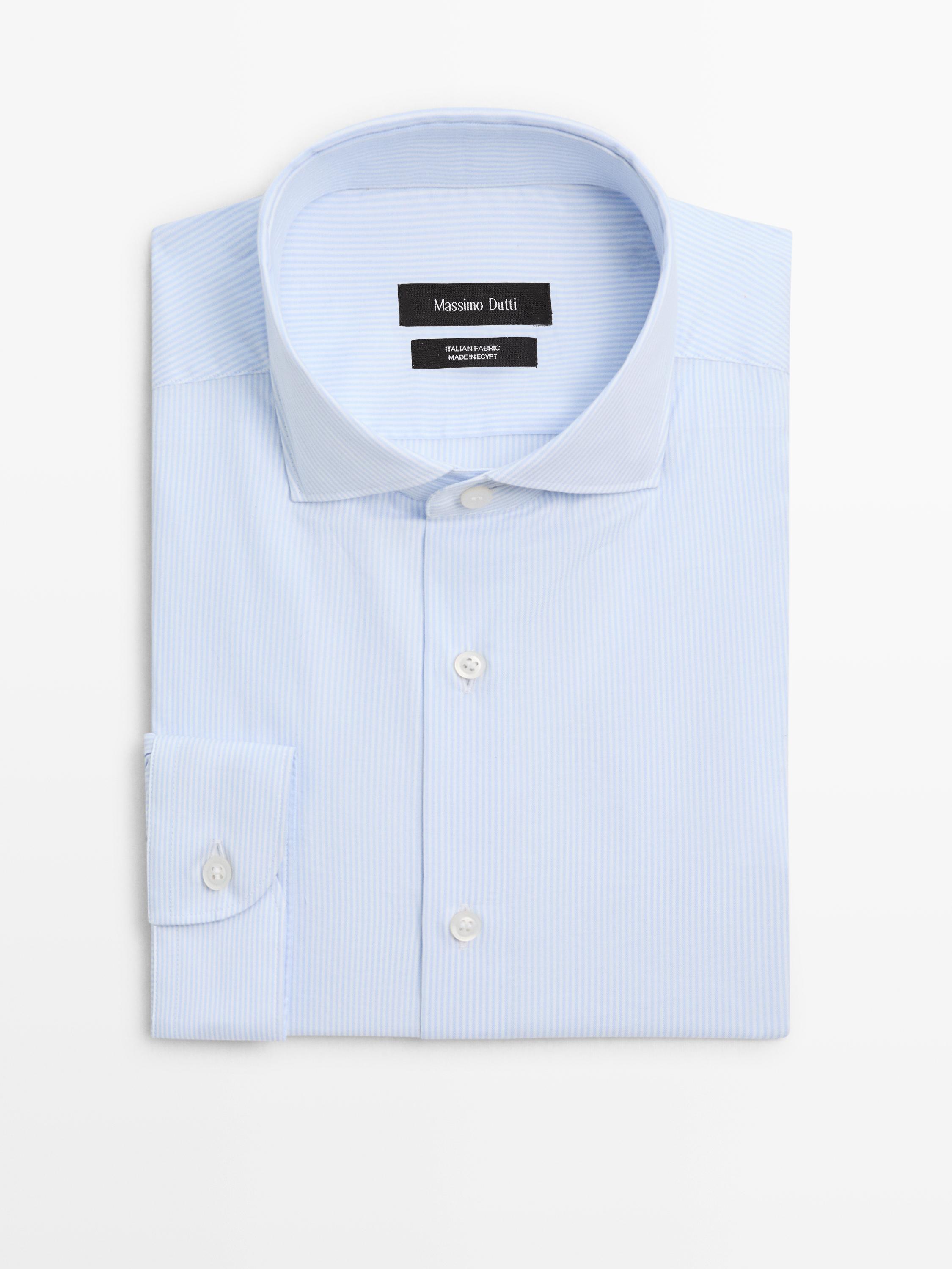 Vista frontal de camisa azul celeste de manga larga con botones blancos y cuello clásico. Texto visible: "Massimo Dutti".