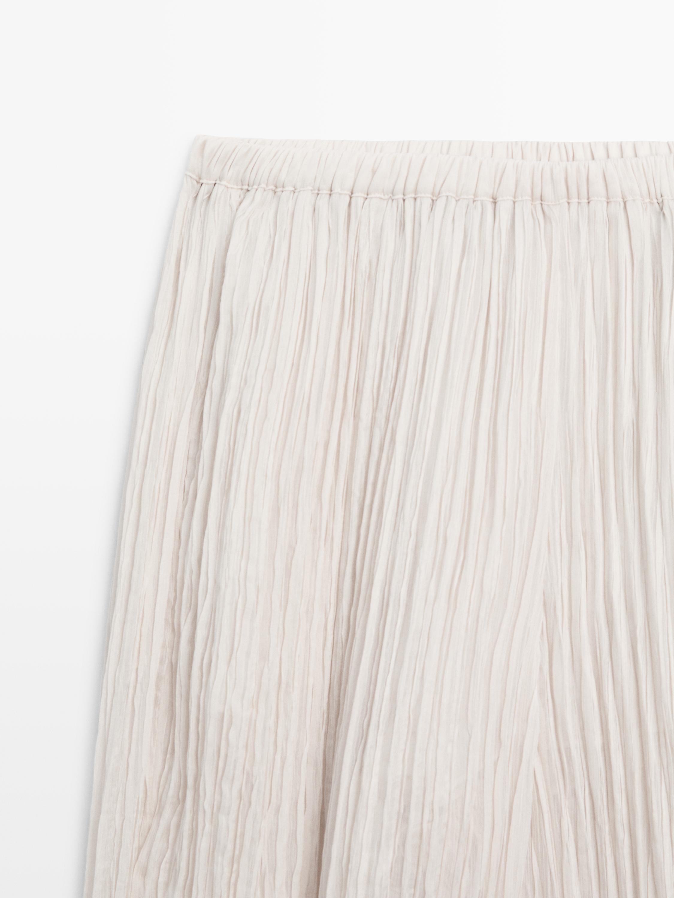 Krem rengi, beli lastikli pileli eteğin orta çekim planı.