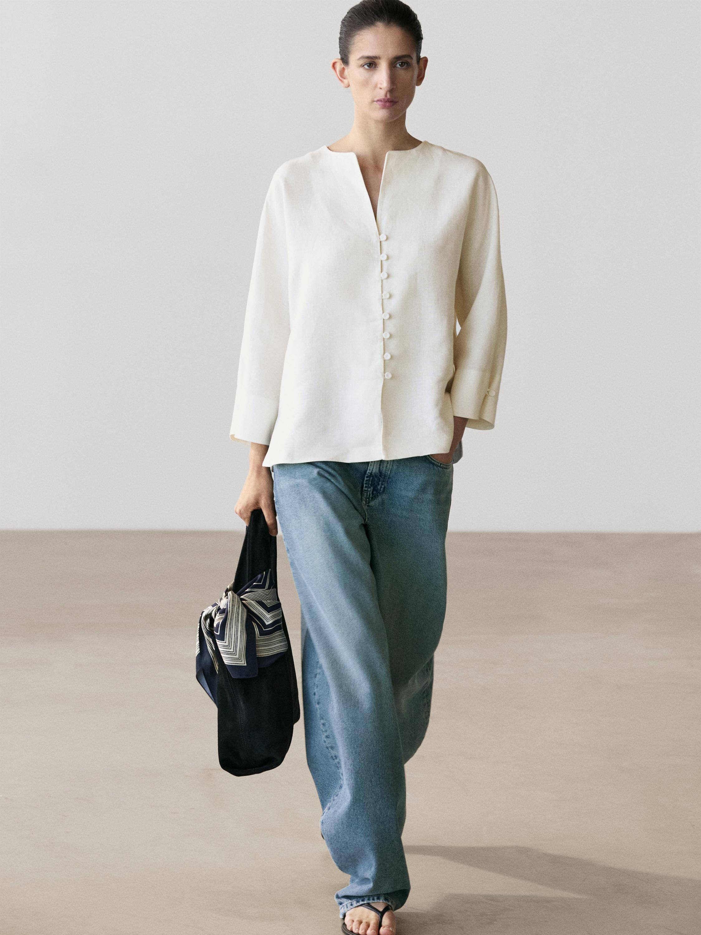 Conjunto de chaqueta blanca con botones frontales y jeans azules.