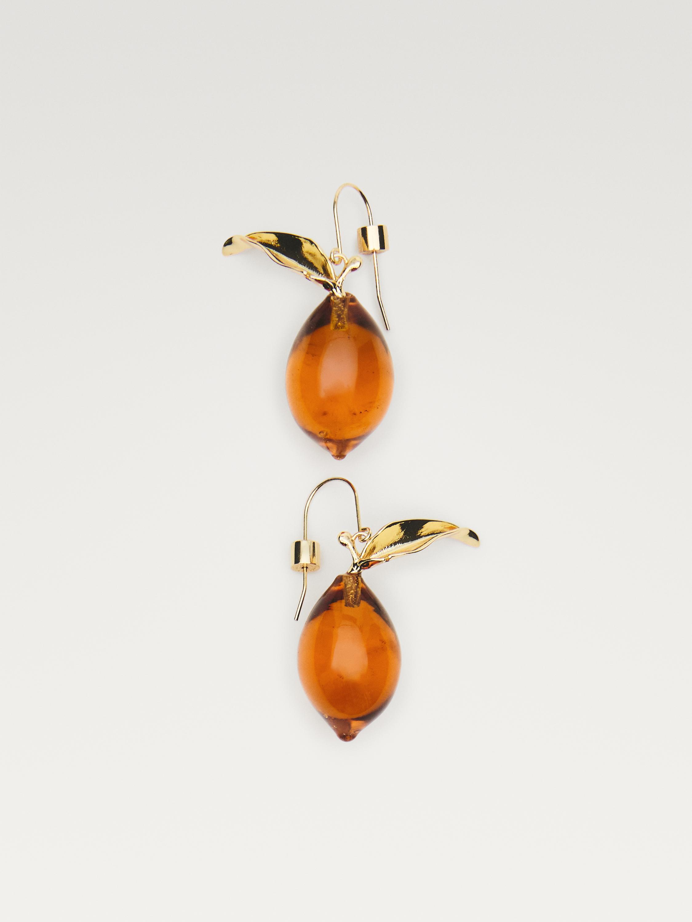 Frontalvisning av gylne øredobber med ravfarget dråpeanheng og metallisk blad-detalj.