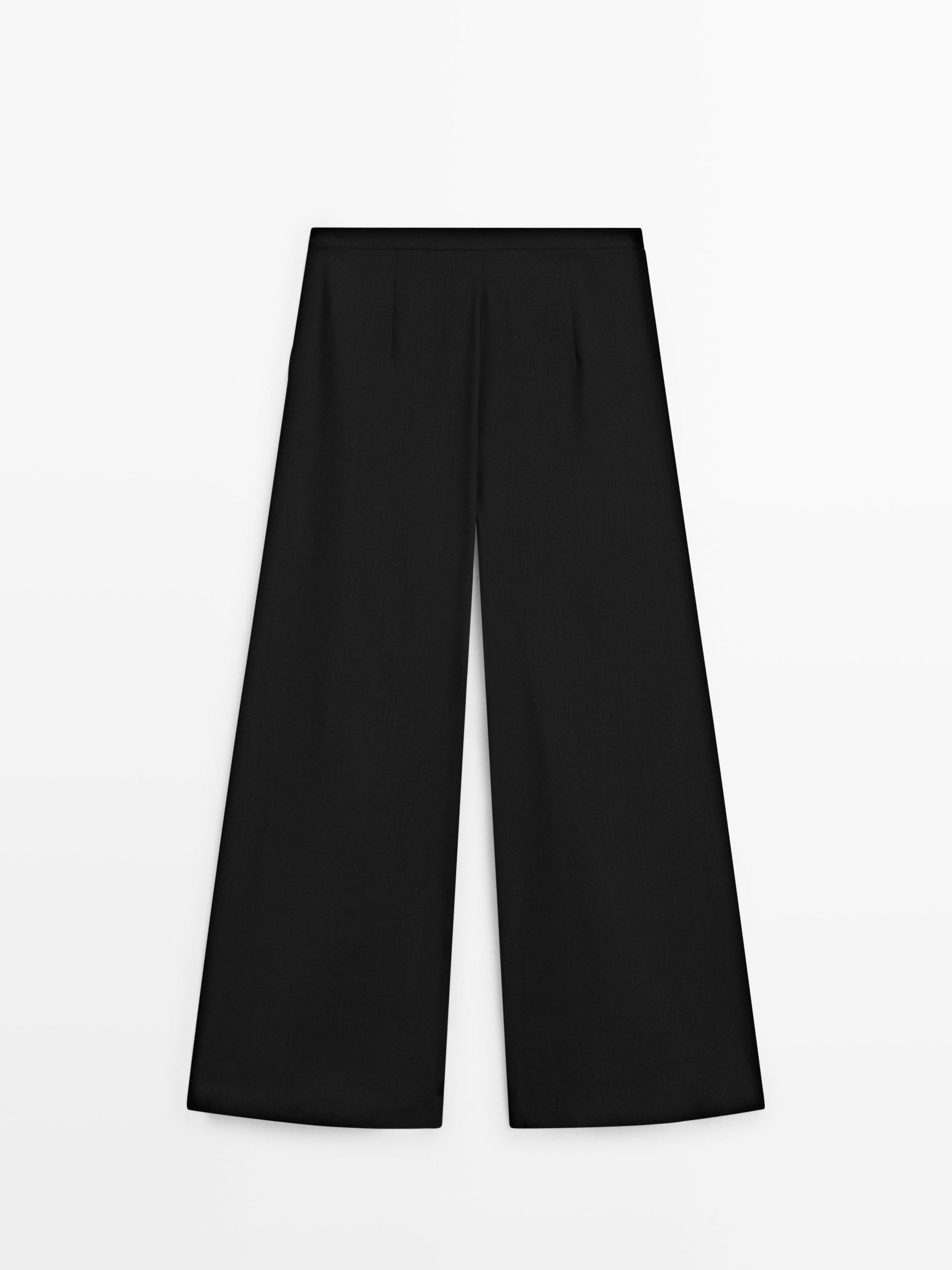 Вигляд спереду: чорні вільні штани зі складками та широкими штанинами.