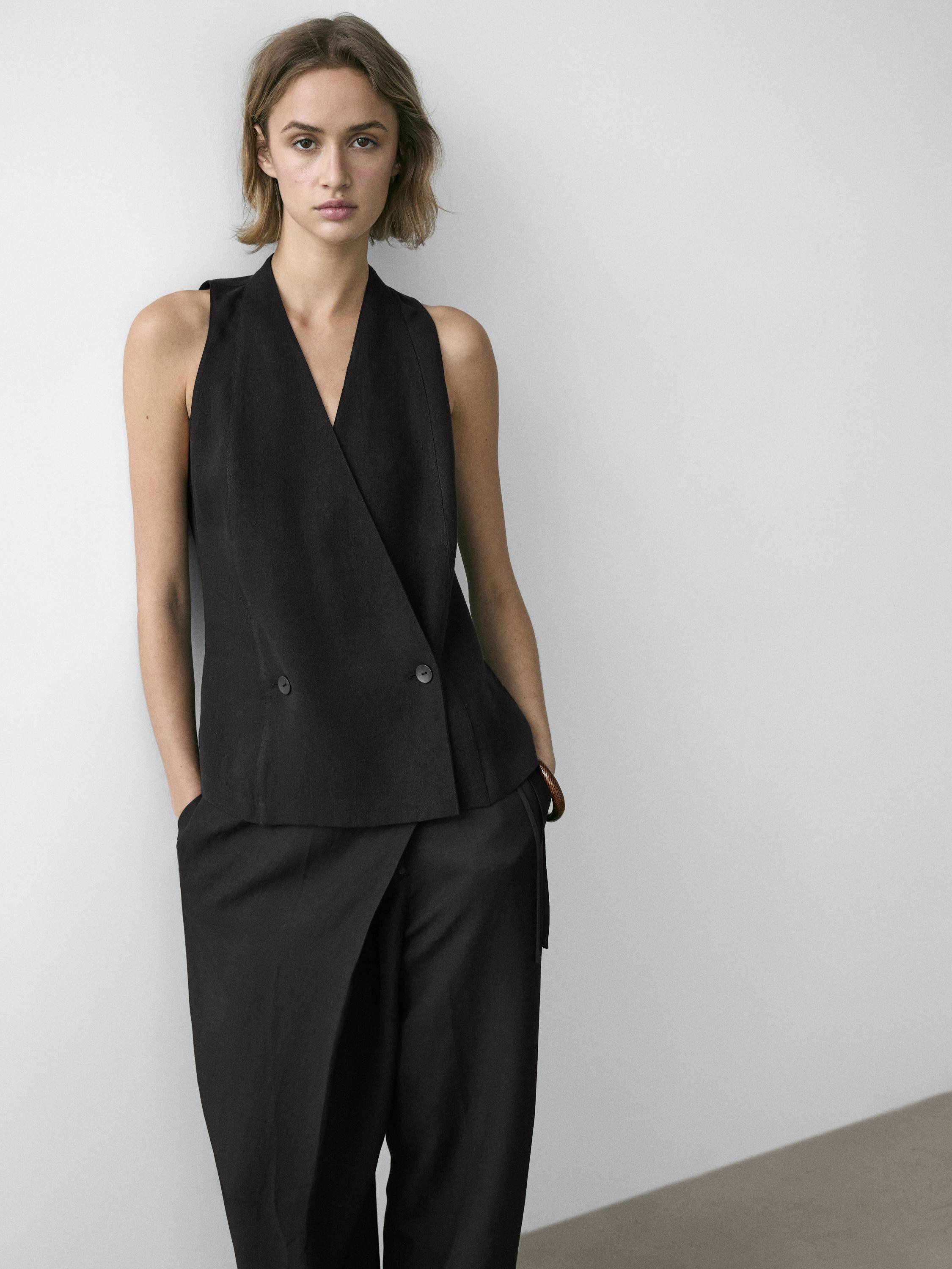 Σετ μαύρο σταυρωτό γιλέκο με λεπτομέρεια κουμπιών και μαύρο παντελόνι φαρδιάς γραμμής.