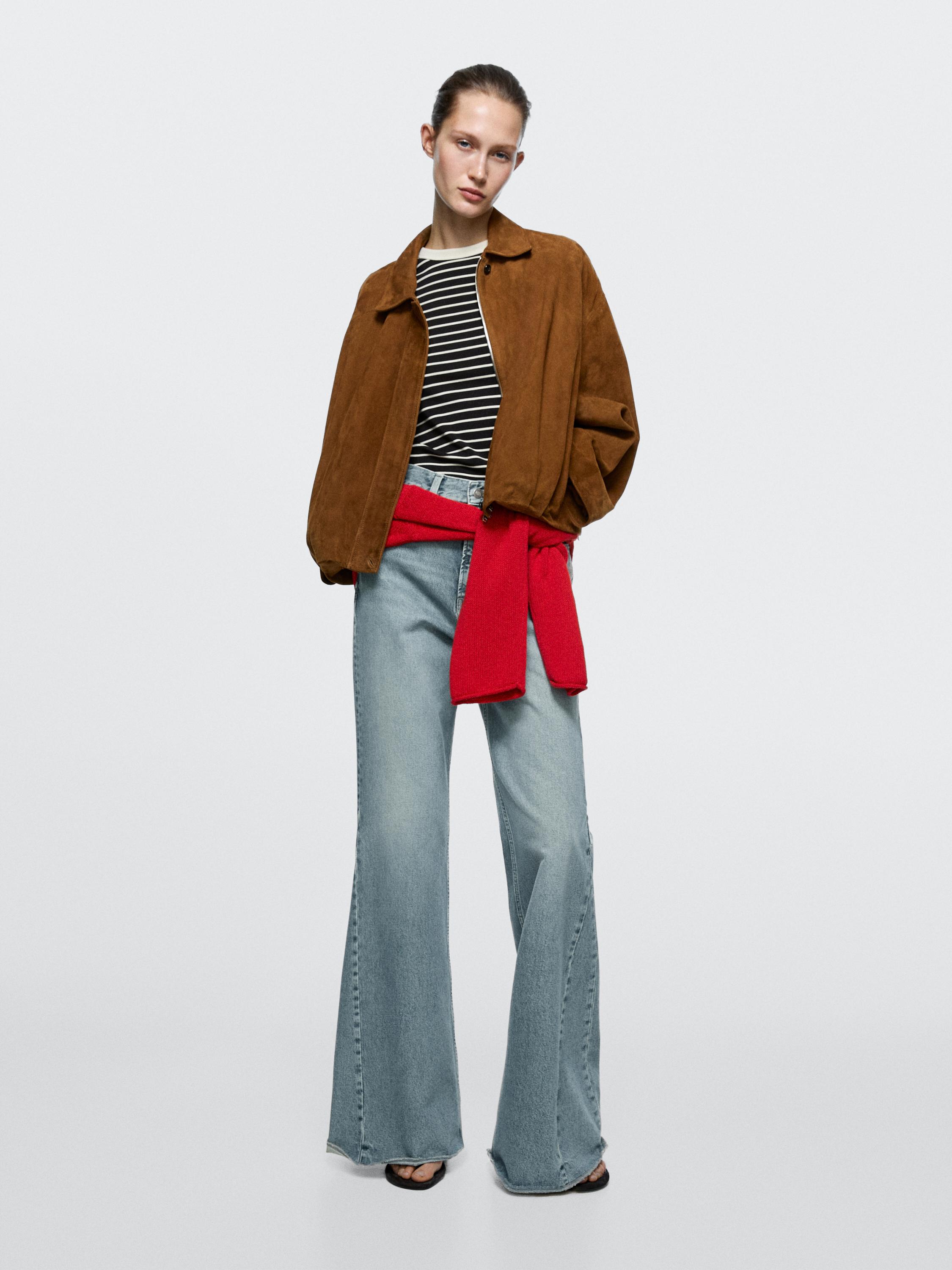 Bruine jas set, gestreept T-shirt, lichtblauwe wide-leg jeans en rode trui om de taille geknoopt.