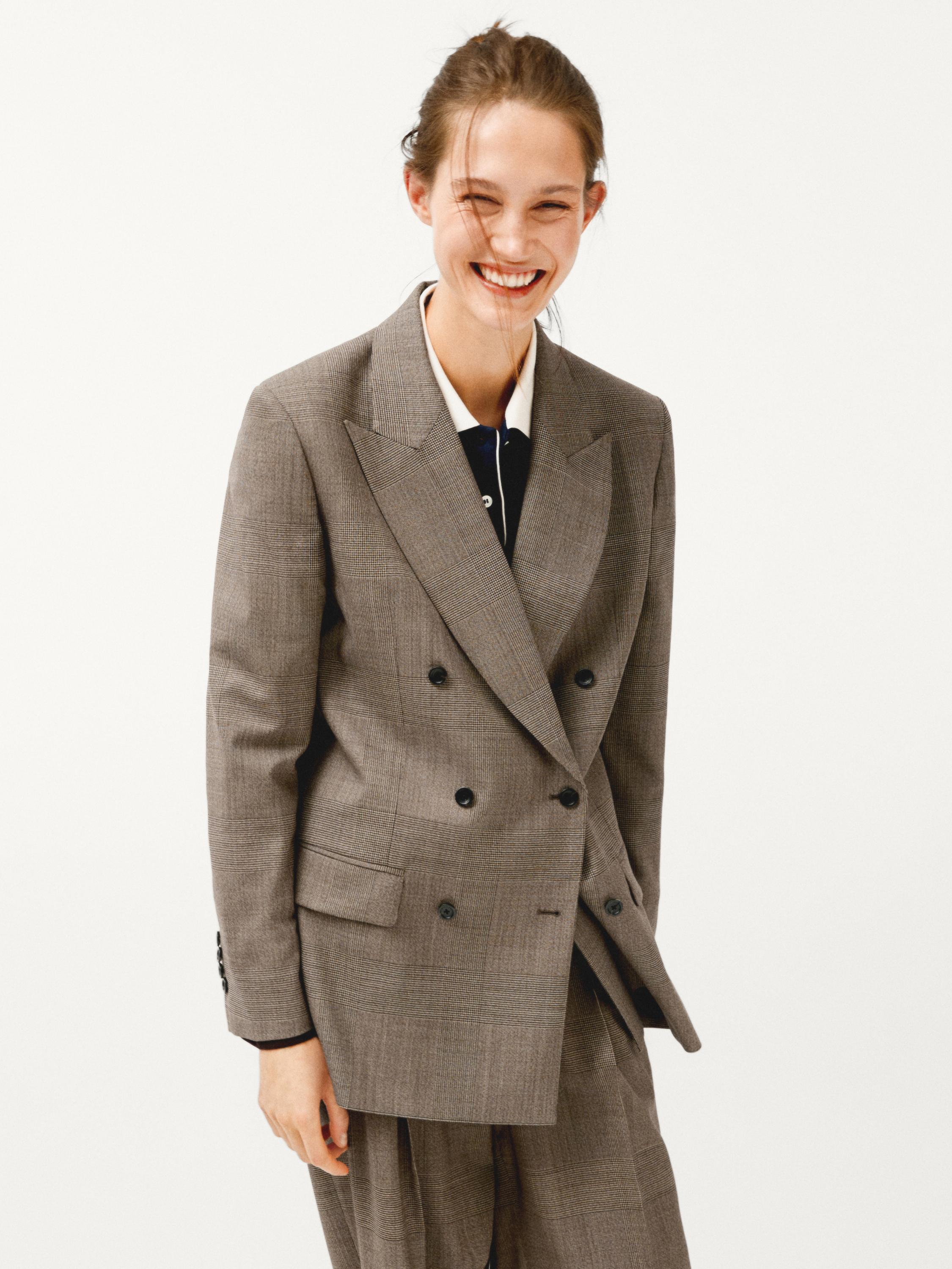 Conjunto de traje marrón de doble botonadura con solapas de pico y bolsillos con solapa. Camisa blanca visible debajo.