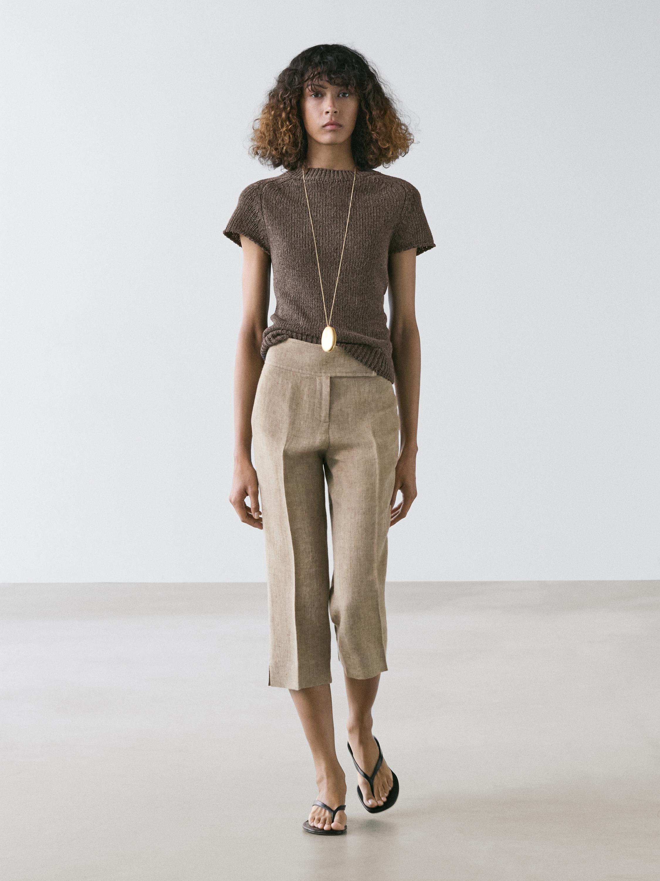 Set aus braunem Kurzarm-Strickpullover und beiger wadenlanger Marlenehose.